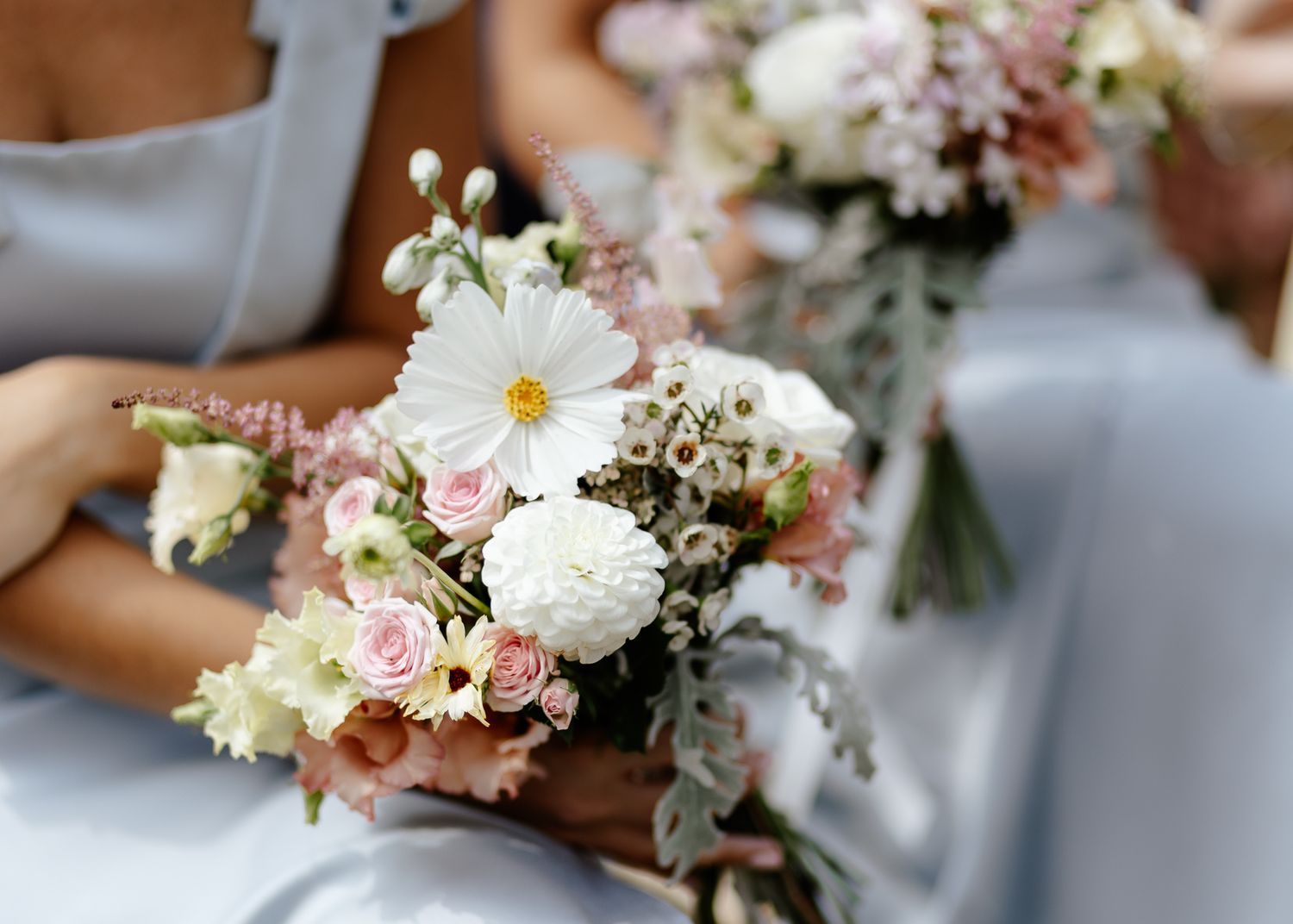 Delicate pink and white floral bouquets with roses and daisies arranged for a wedding celebration.