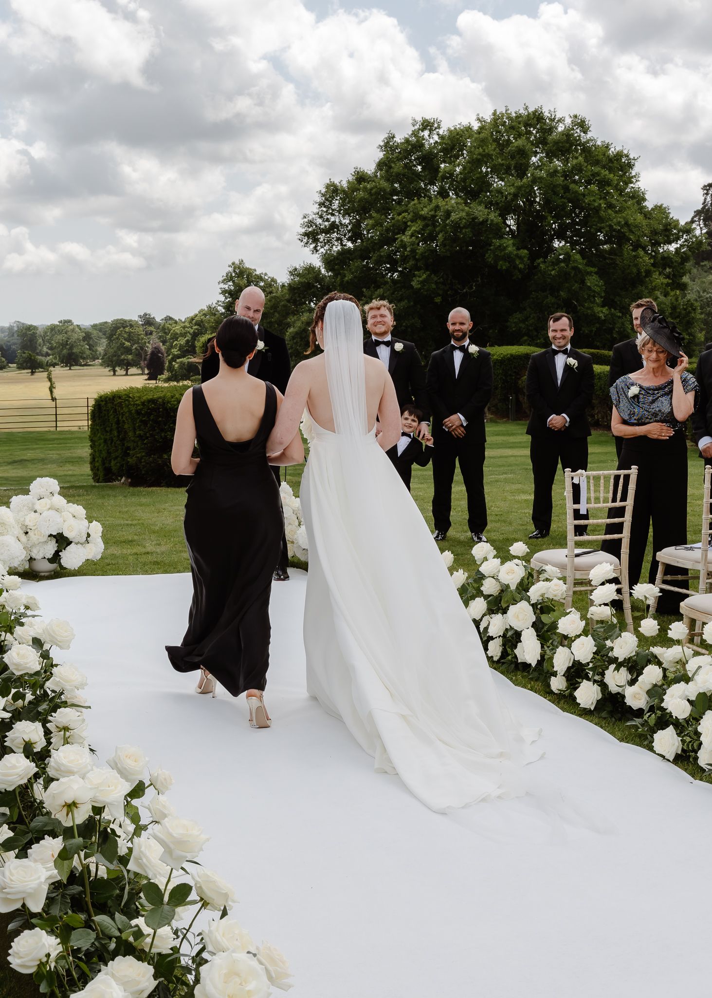 Elegant outdoor wedding ceremony setup with white floral arrangements and a pristine white aisle runner.