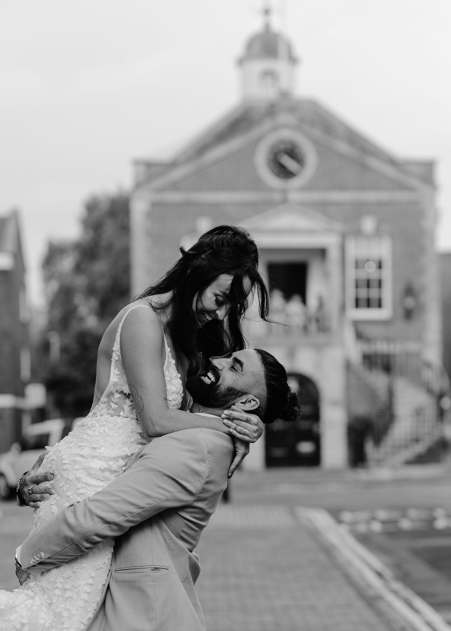A couple shares romantic kisses in front of a church building in black and white photography.