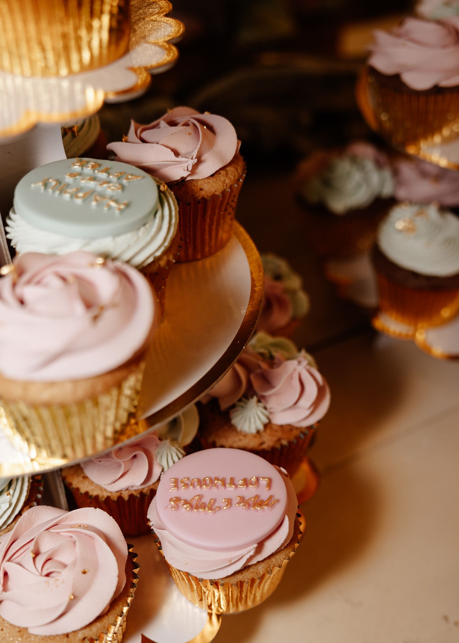 Pink frosted cupcakes with delicate pearl decorations arranged in rows on a display table.