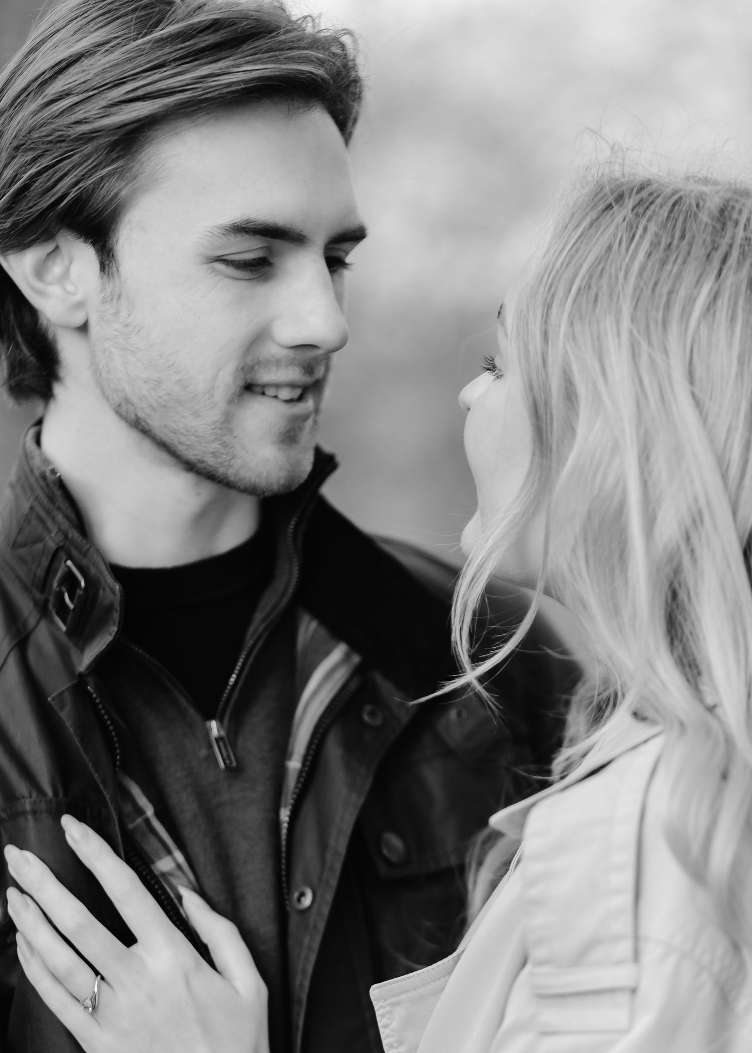 Black and white photo of a young couple sharing a romantic moment, smiling and gazing at each other closely.