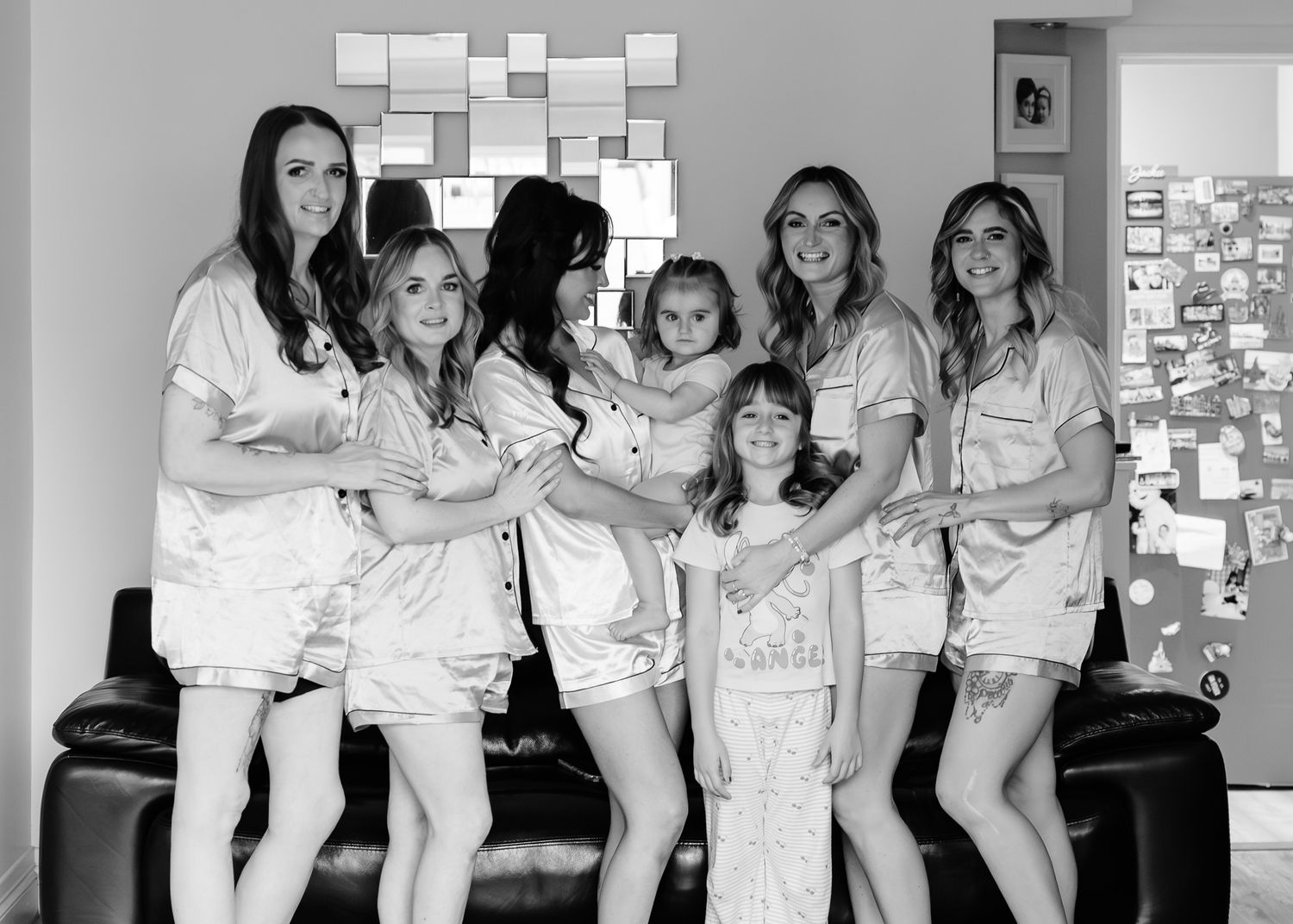 A group of people wearing matching white pajama sets pose together in a black and white photo.