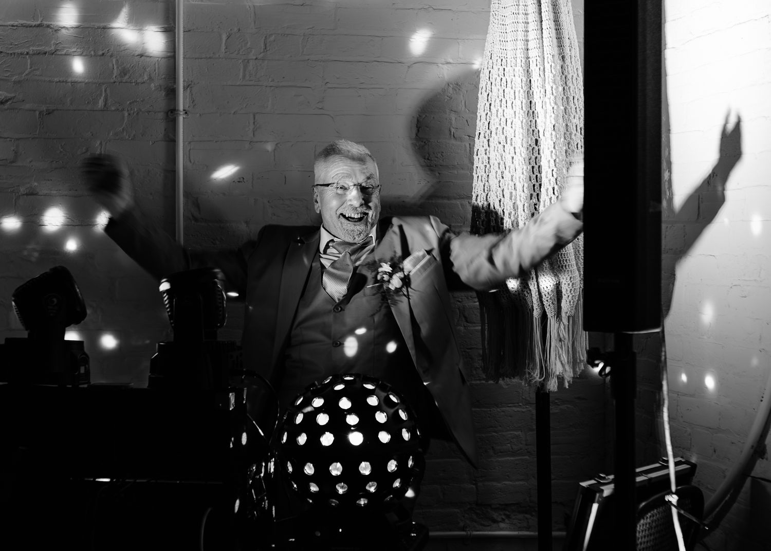 Black and white wedding reception photo with dramatic lighting and dancing silhouettes.