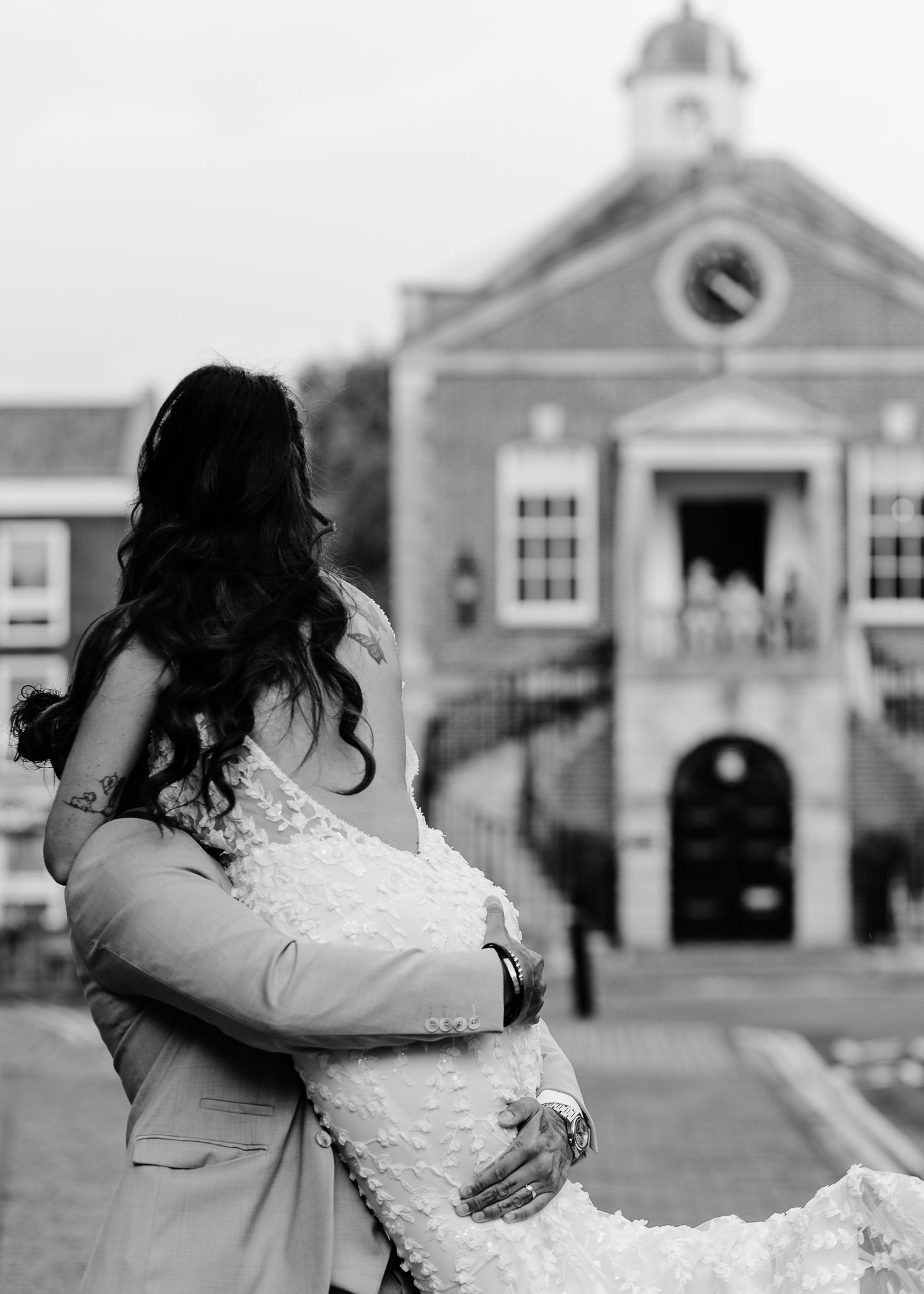 A series of four black and white photos showing a couple embracing in front of a building facade.