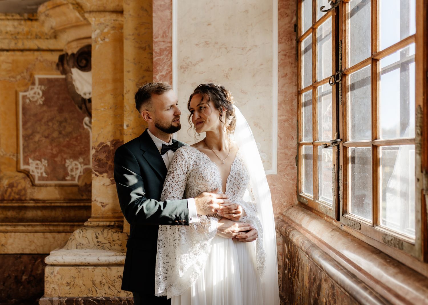 A series of wedding photographs capturing tender moments by sunlit windows in an elegant vintage building.