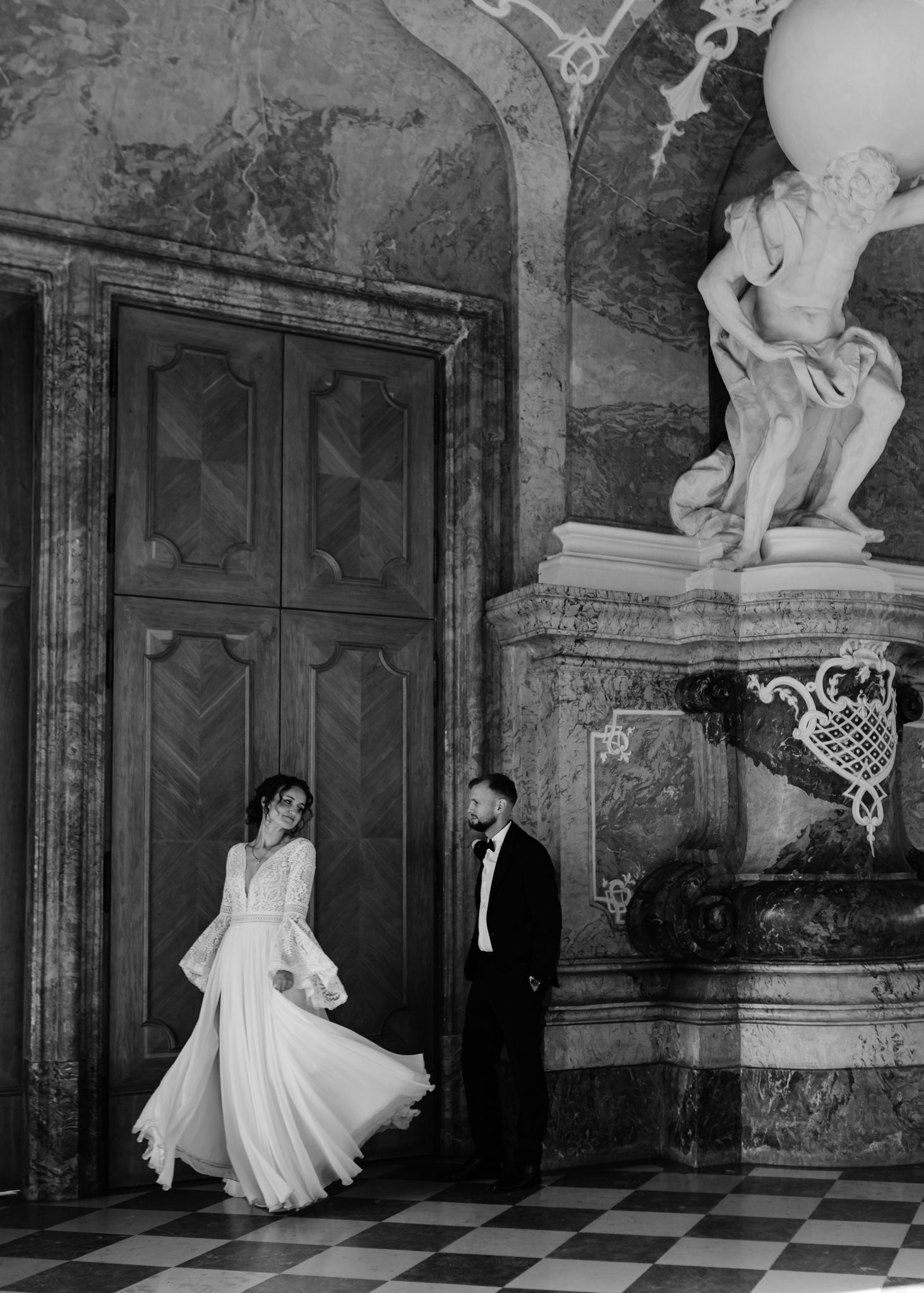 Black and white photo series of a couple dancing in a grand historic hall with marble floors and statues.