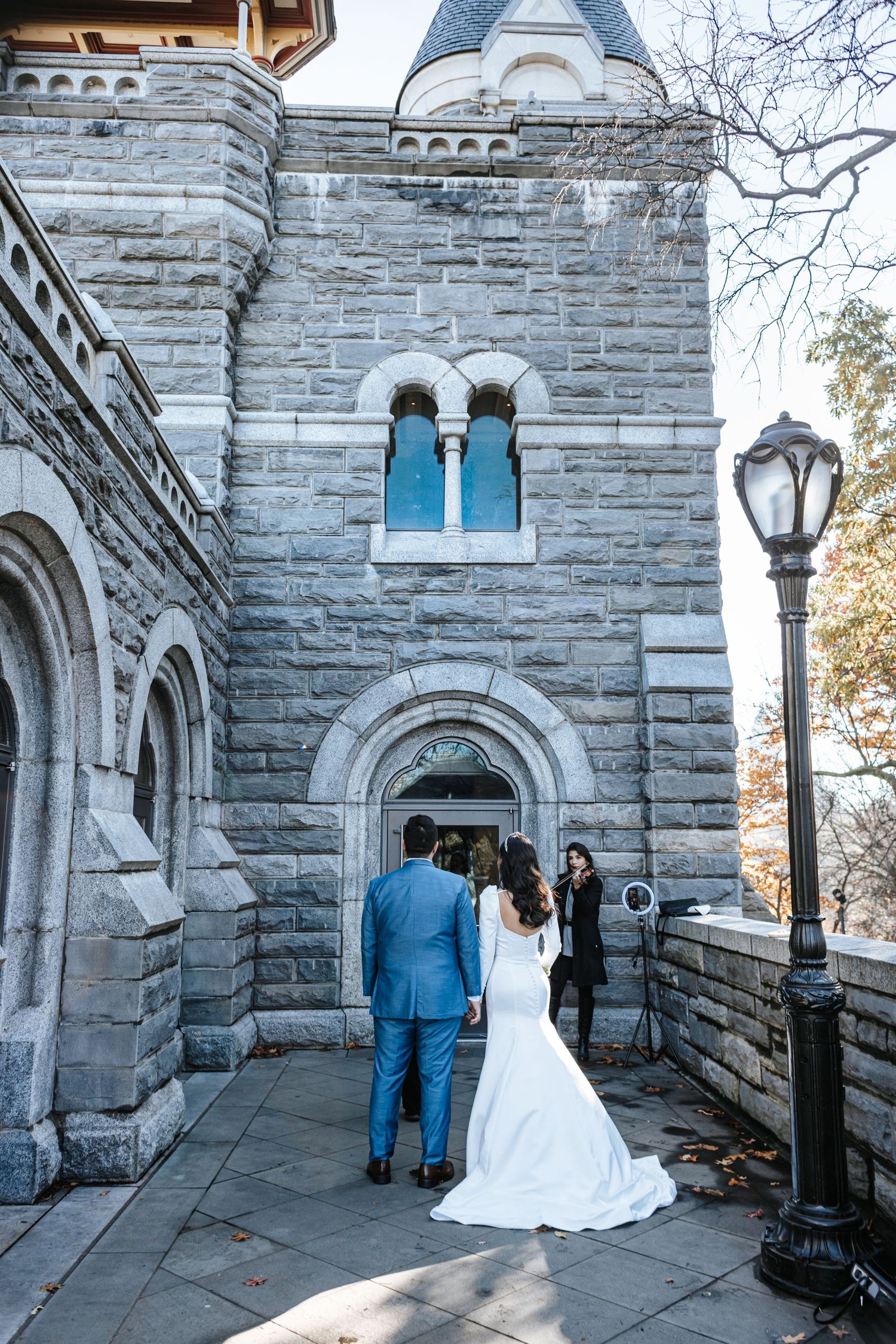 Bride and groom standing before a stone castle entrance during their Central Park wedding.