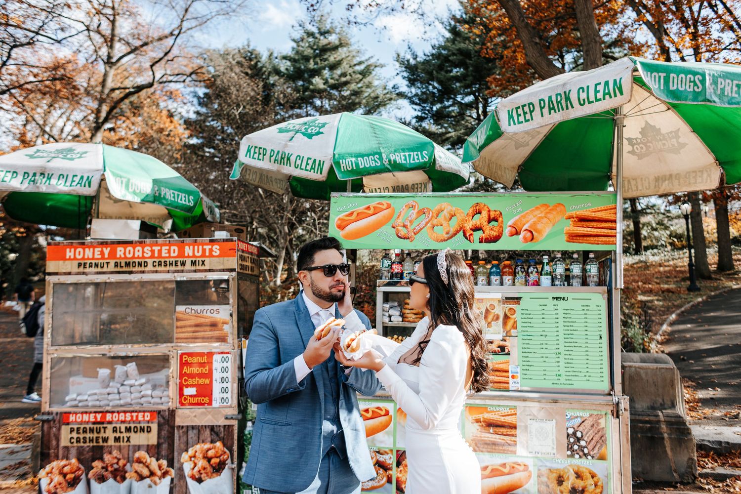 Newlywed couple shares hot dogs from a Central Park street food cart on their wedding day.