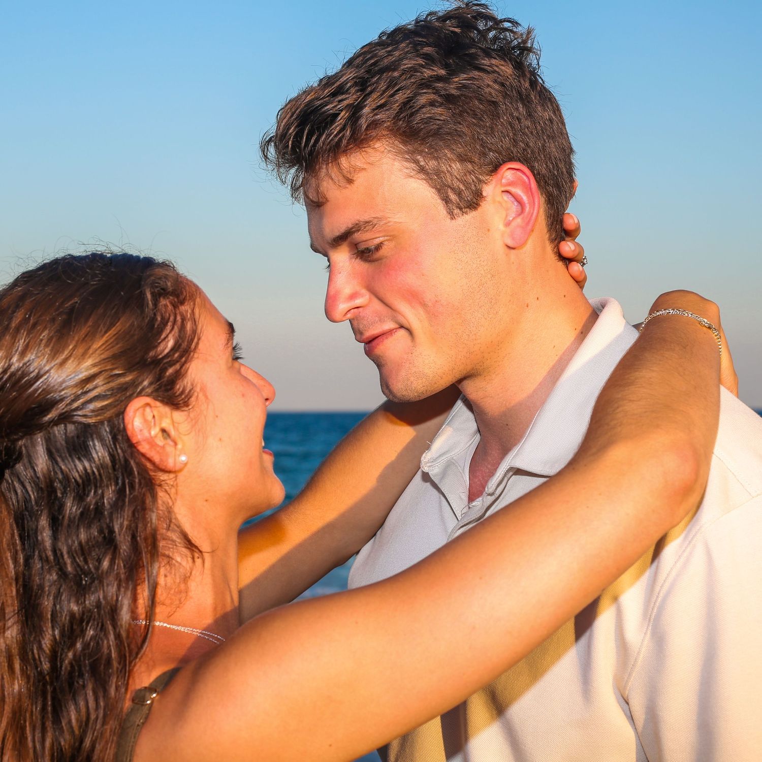 Romantic beach portraits showing tender moments between a couple against ocean backdrop.