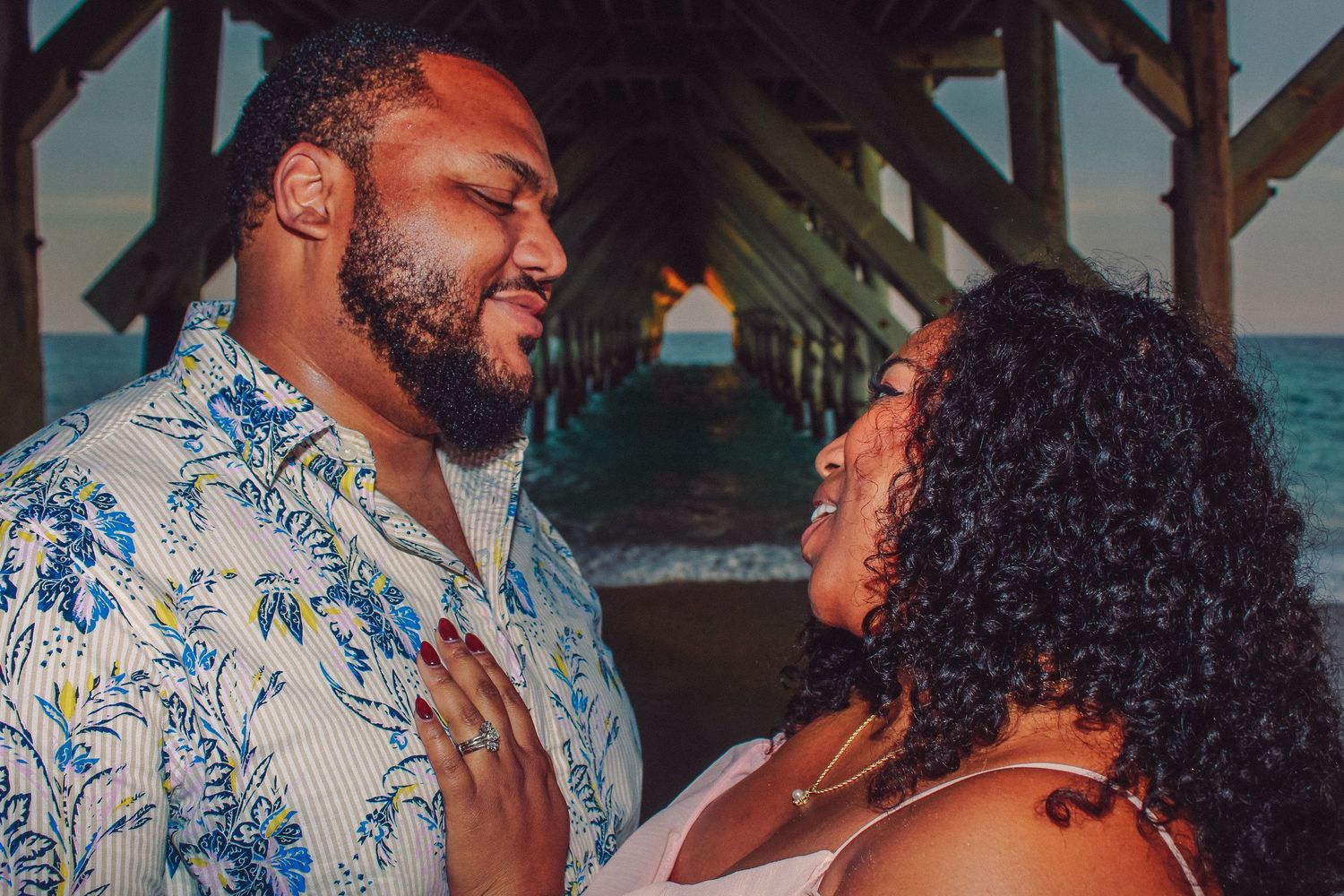 Couple sharing a romantic moment at sunset by the ocean.