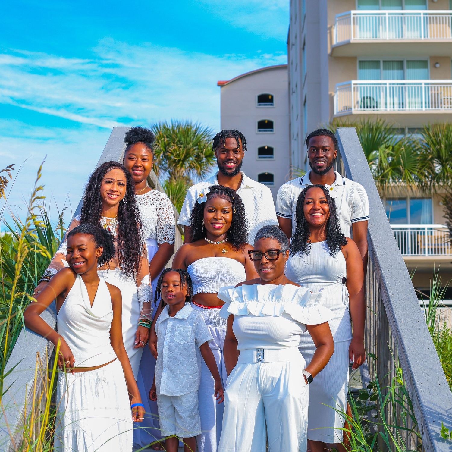 Family group photo on beach with everyone wearing coordinated white outfits.