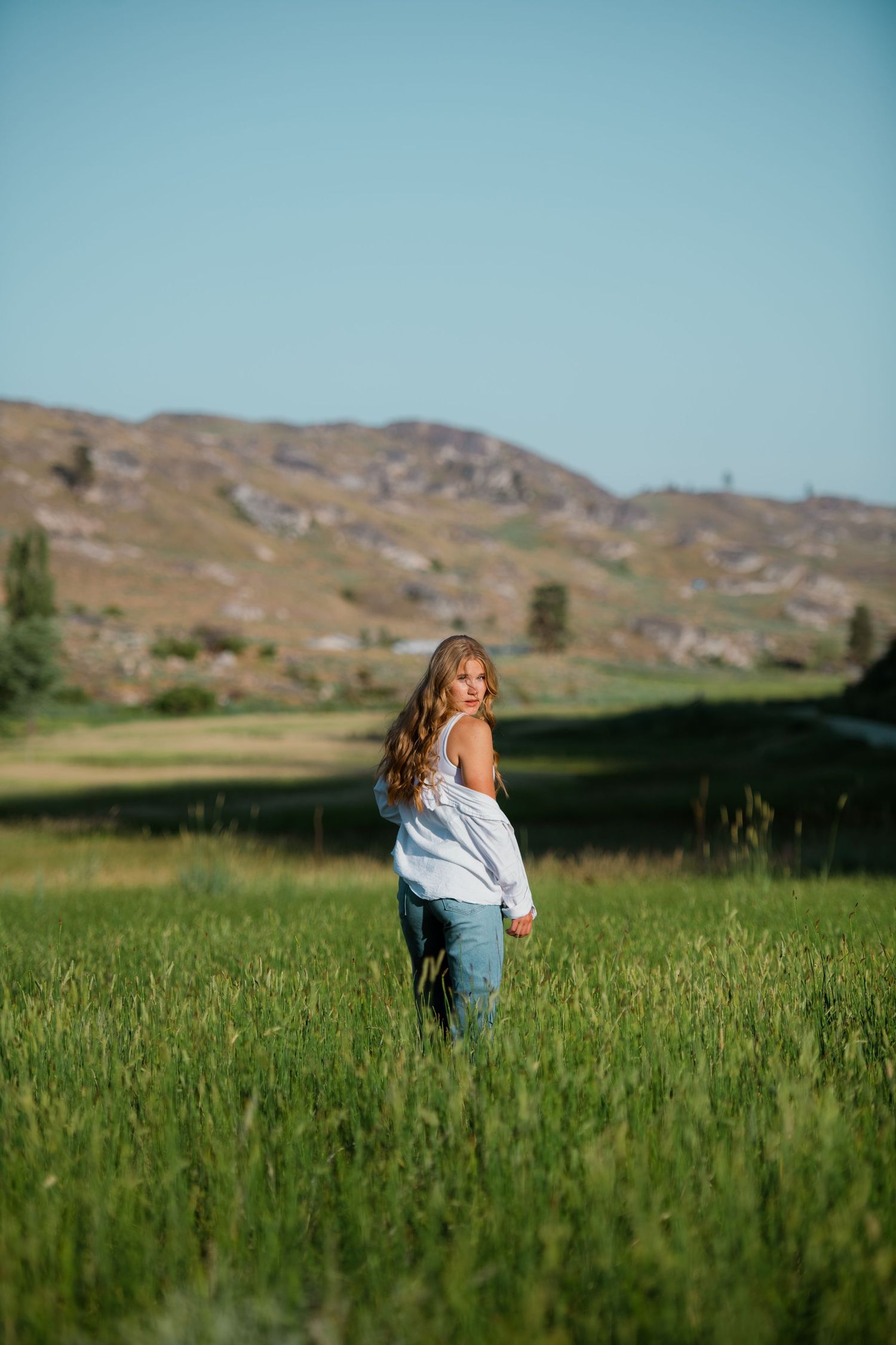 Brewster High School senior walking through the valley grasses below the foothills in north-central Washington before the start of summer.