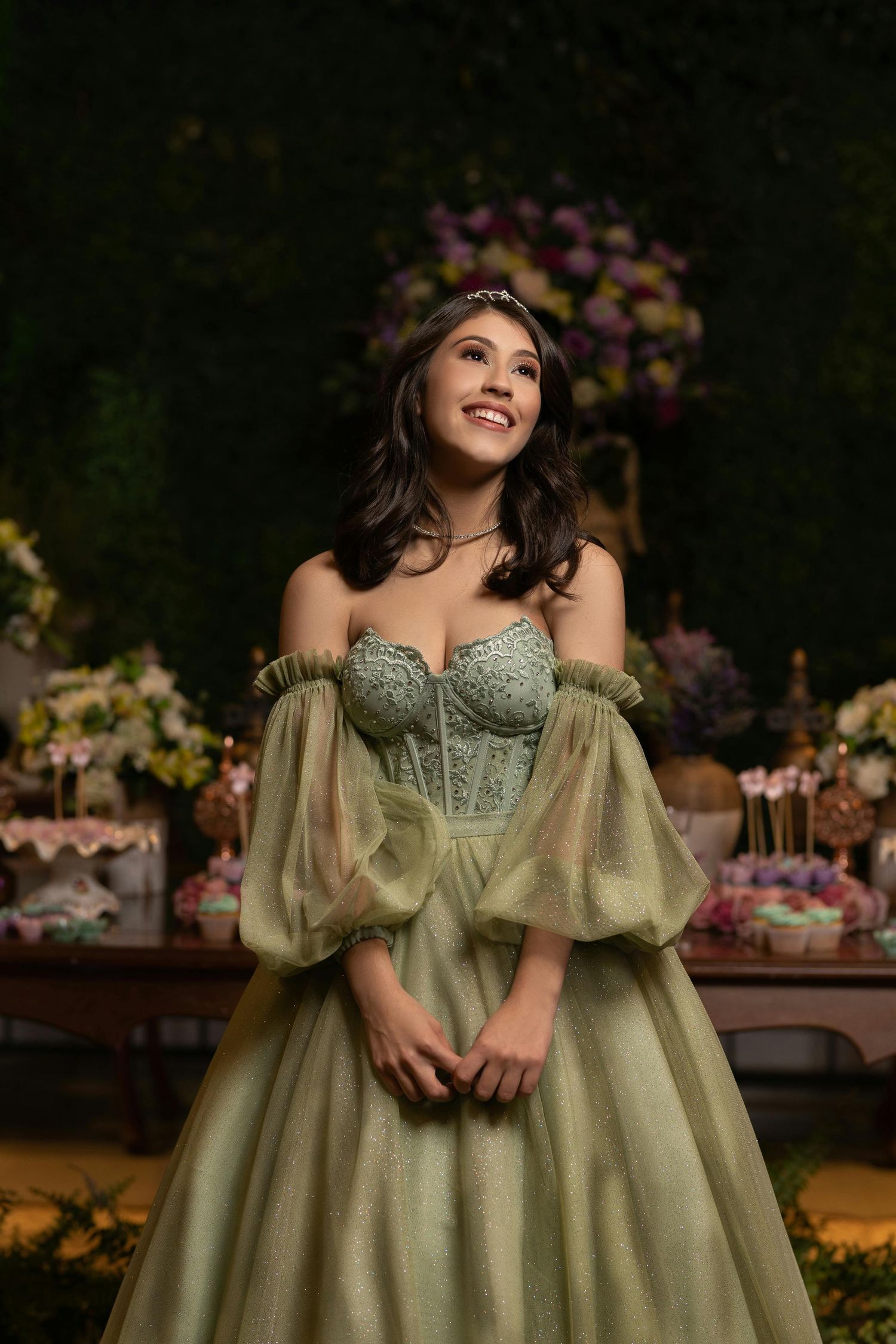 Elegant green ball gown with off-shoulder design and beaded bodice in romantic setting.