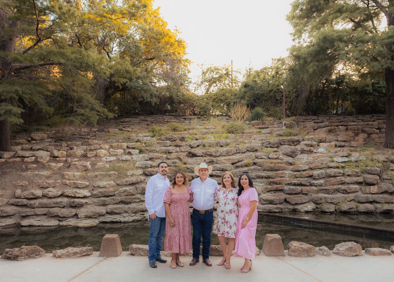 A family group poses together on stone steps during a golden hour photoshoot.