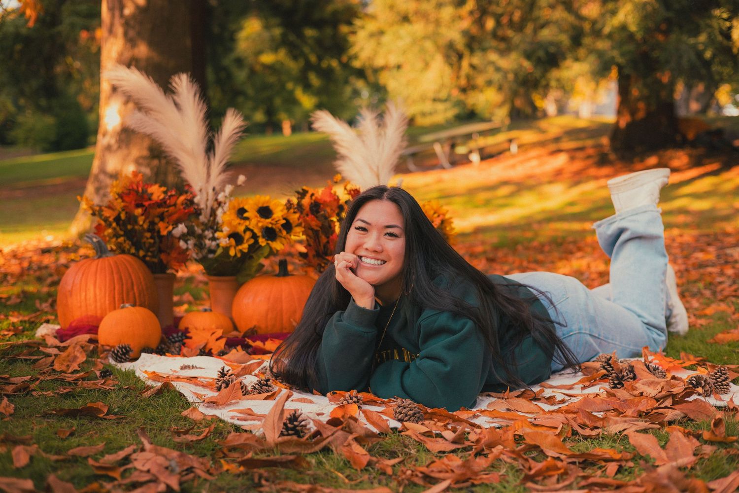 Fall photography session among orange leaves and pumpkins on ground.