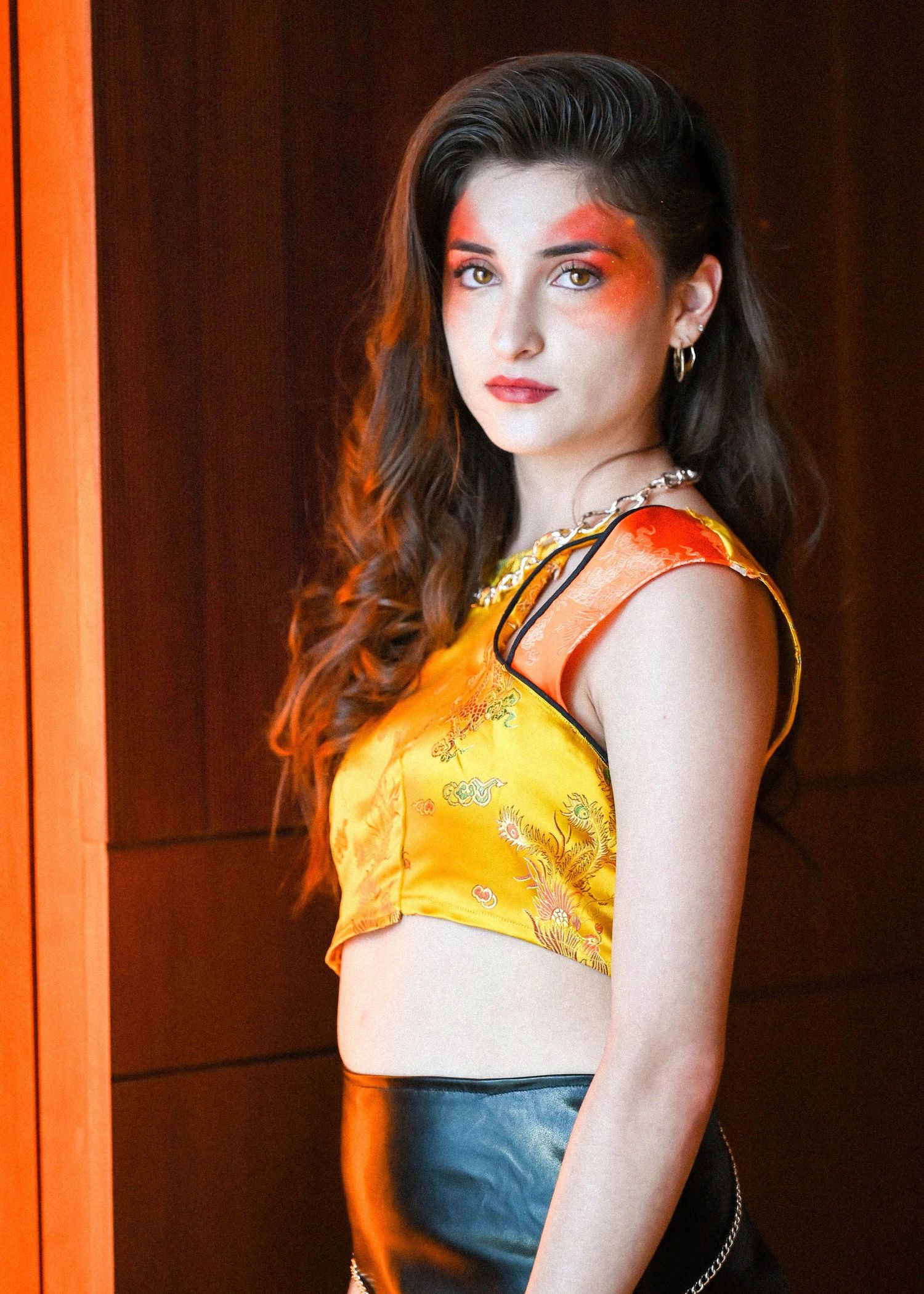 Fashion portraits with dramatic orange lighting and yellow top against dark background.