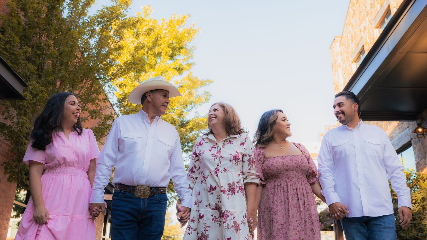 Family gathering outdoors with autumn trees and golden sunlight in background.