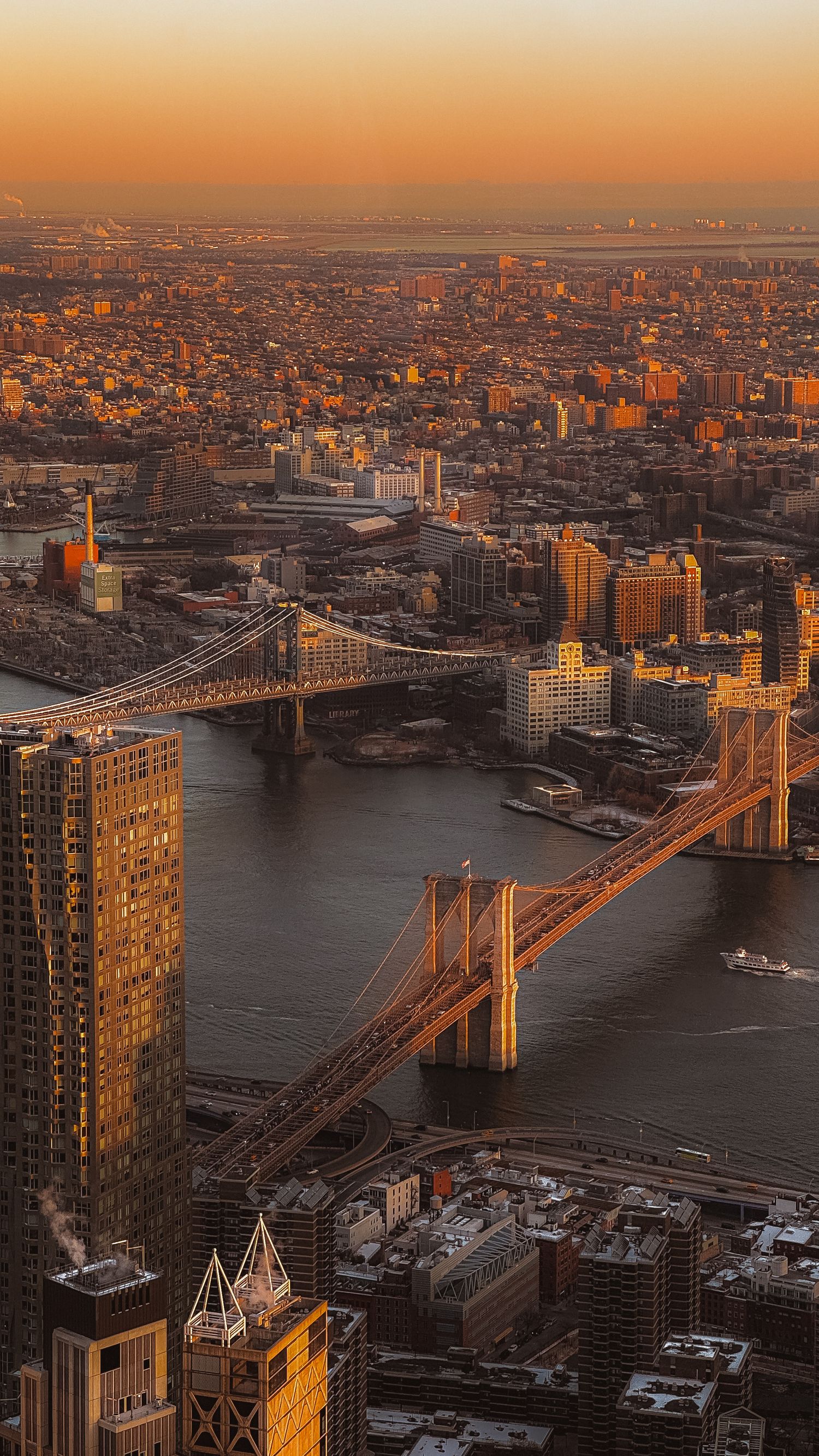Aerial view of Manhattan Bridge and NYC skyline during golden sunset.