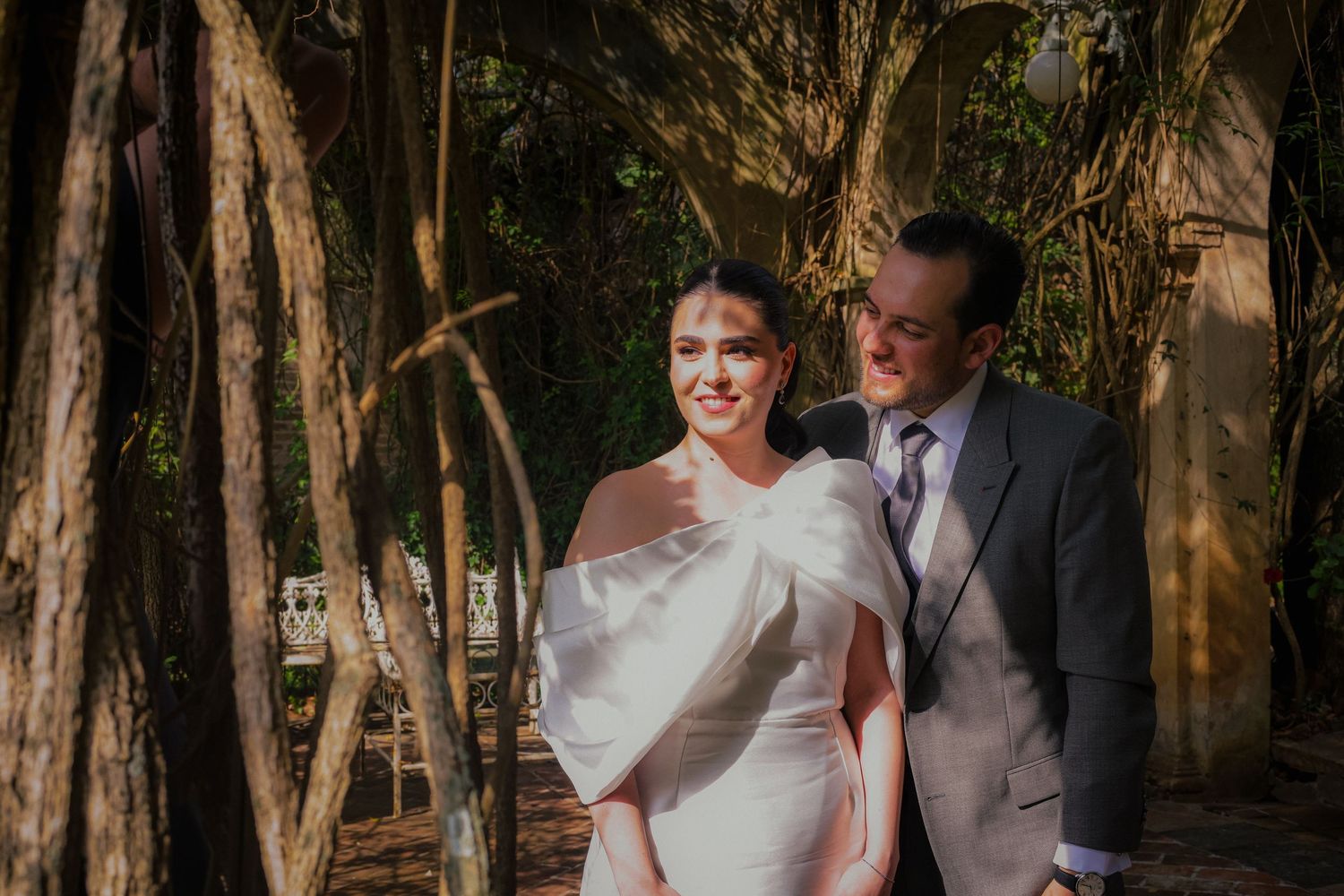 Candid wedding photo in a natural woodland setting with dappled sunlight.