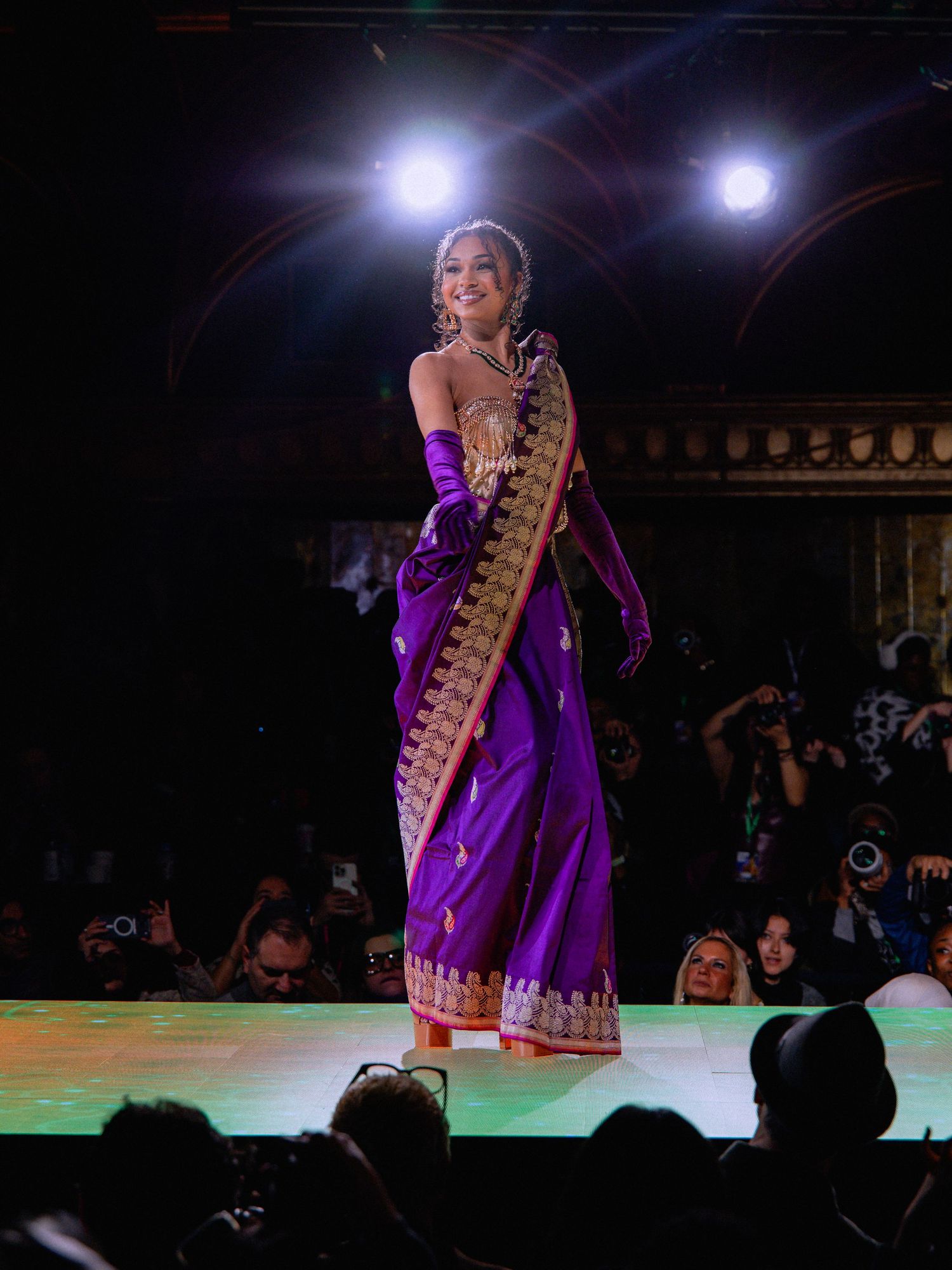 A performer in a purple dress plays a traditional stringed instrument on stage during a cultural performance.