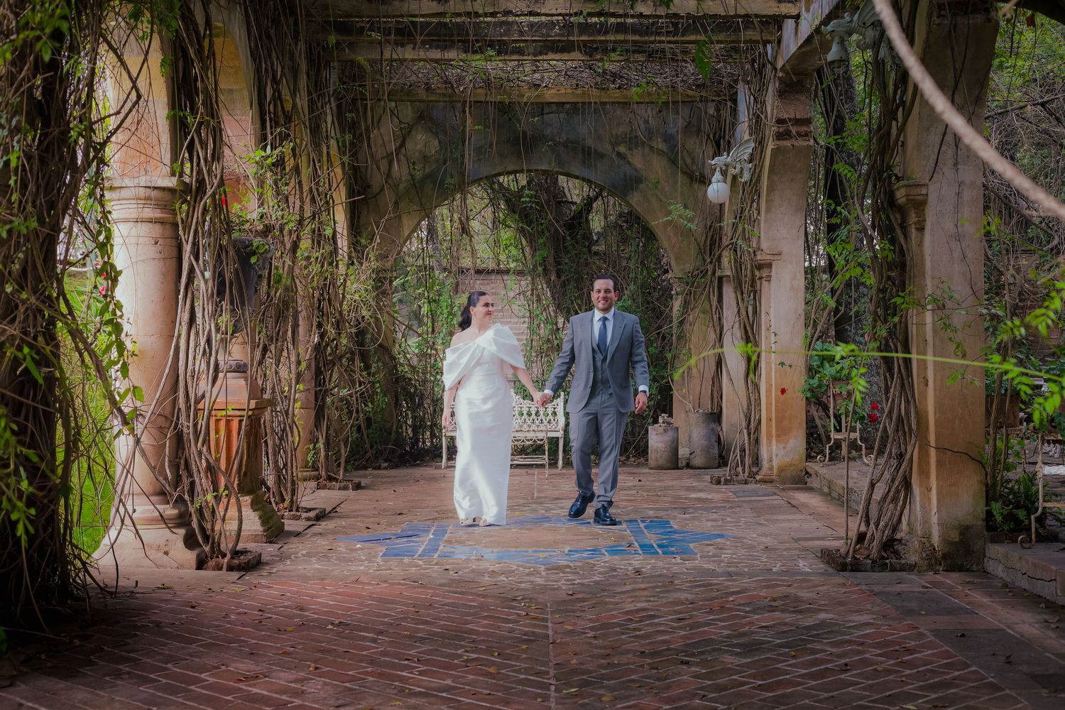 Elegant couple strolling through a vine-covered garden walkway.