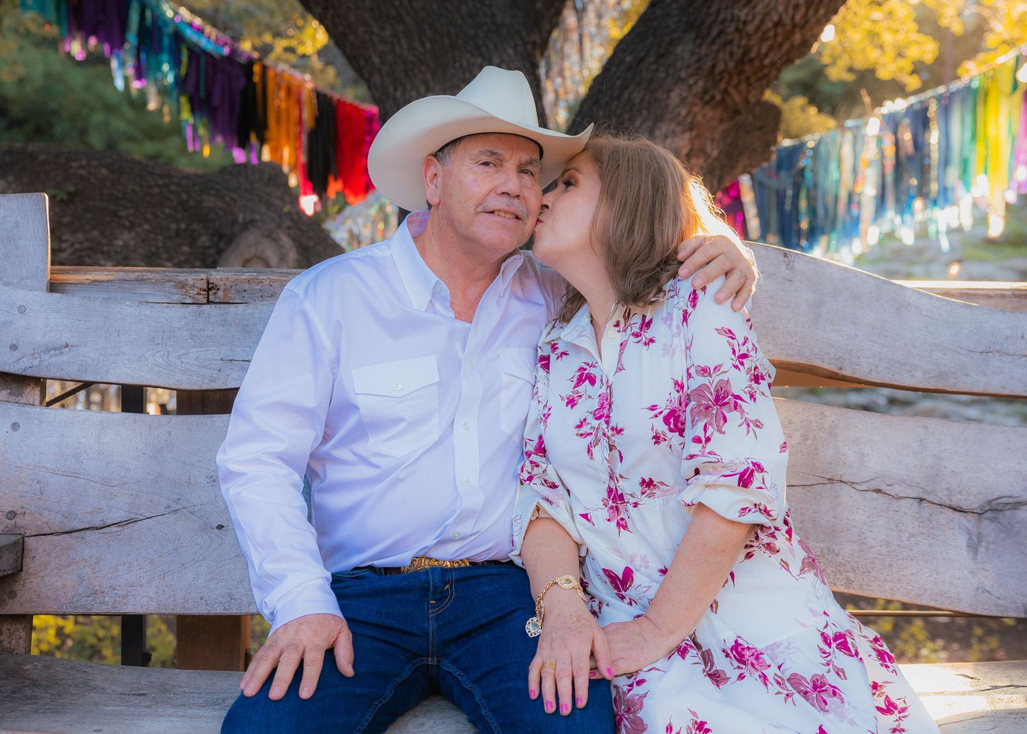 Family photoshoot with decorative banners and rustic fence during sunset.