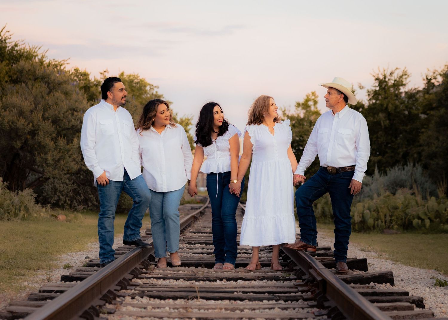 Group sitting together on railroad tracks at sunset creating a casual outdoor photo series.