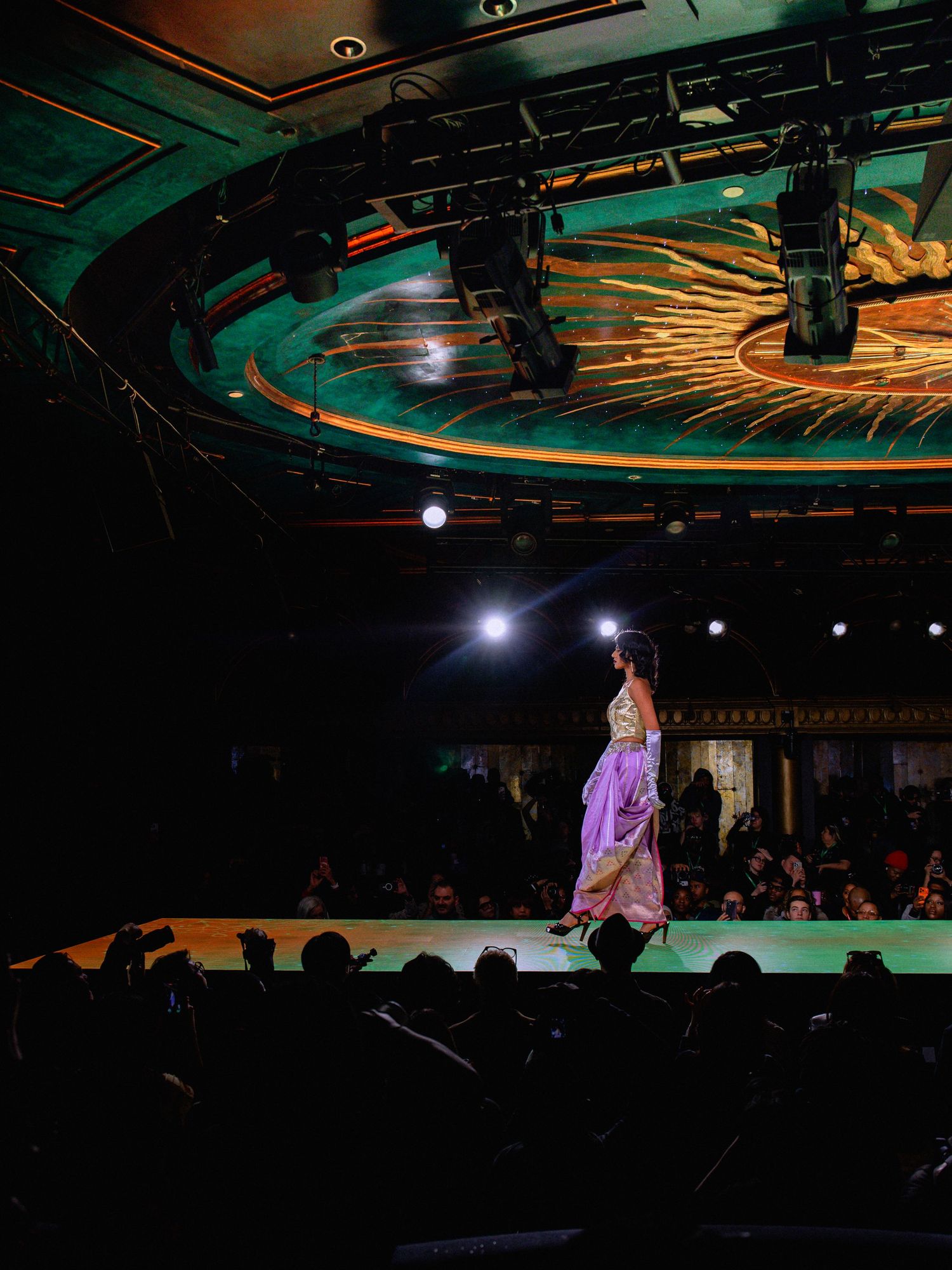 Stage lighting creates dramatic silhouettes and colorful effects during a live performance in a dark venue.