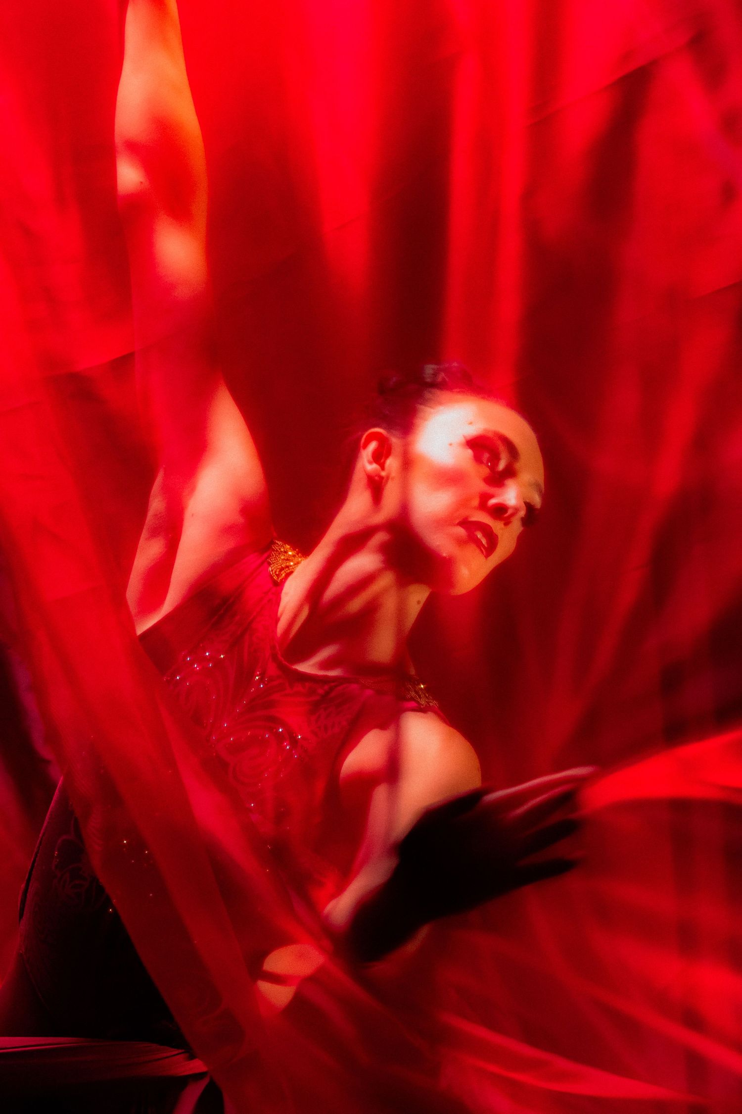 Dramatic dance performance with flowing red fabric and moody lighting creates artistic silhouette.