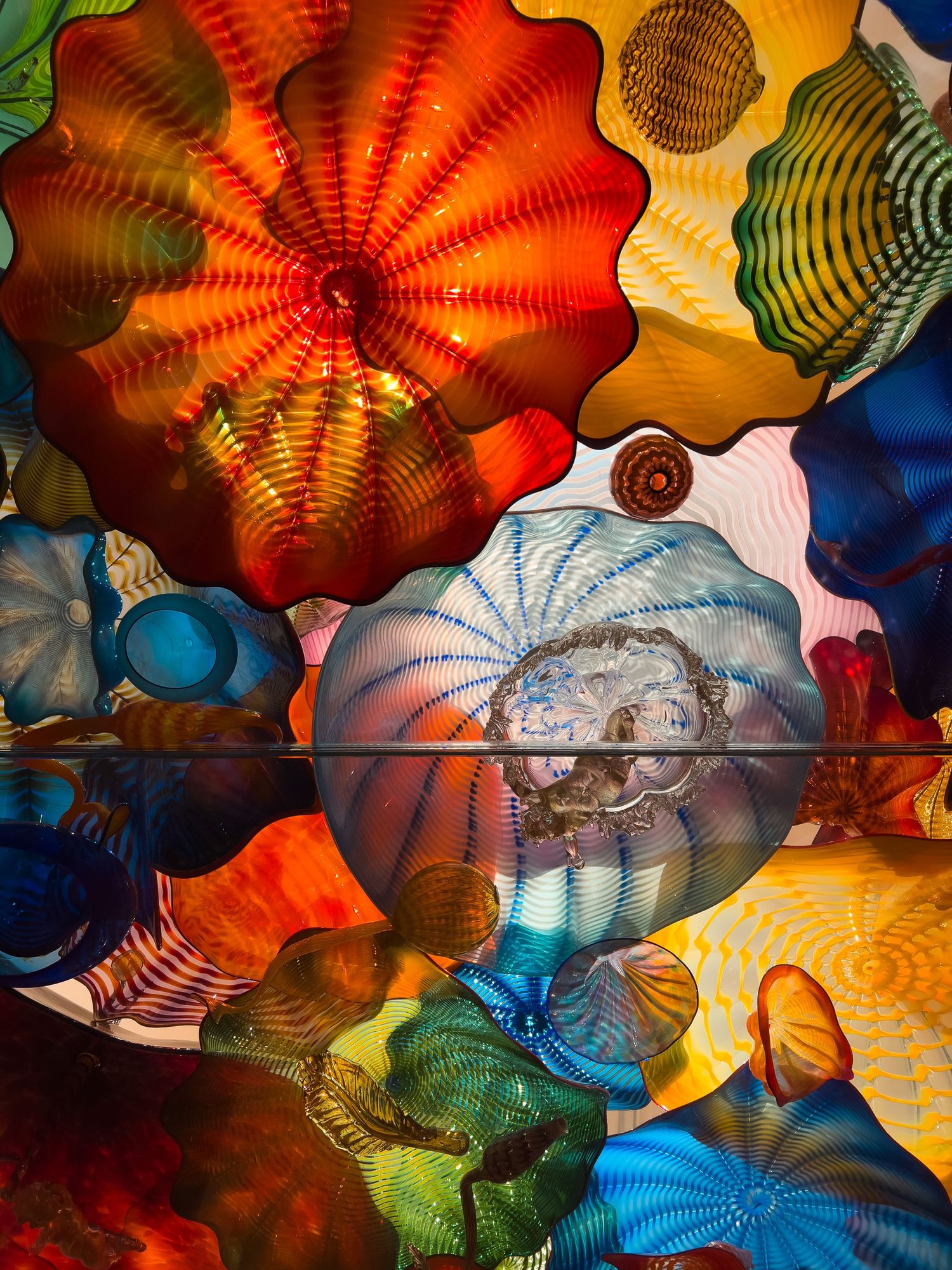 Colorful glass art installation featuring vibrant red, blue, and orange blown glass pieces.