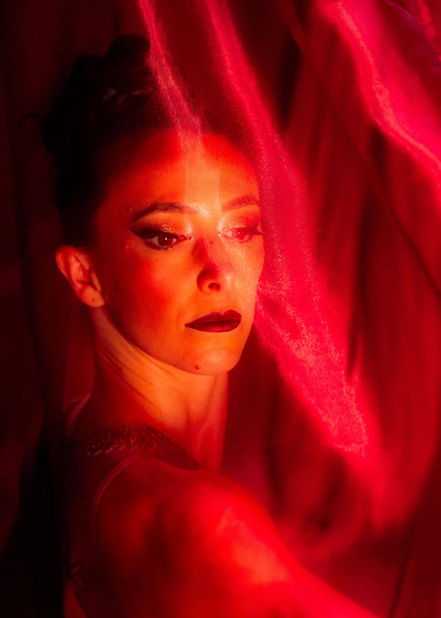 Artistic portrait with dramatic red lighting and shadows.