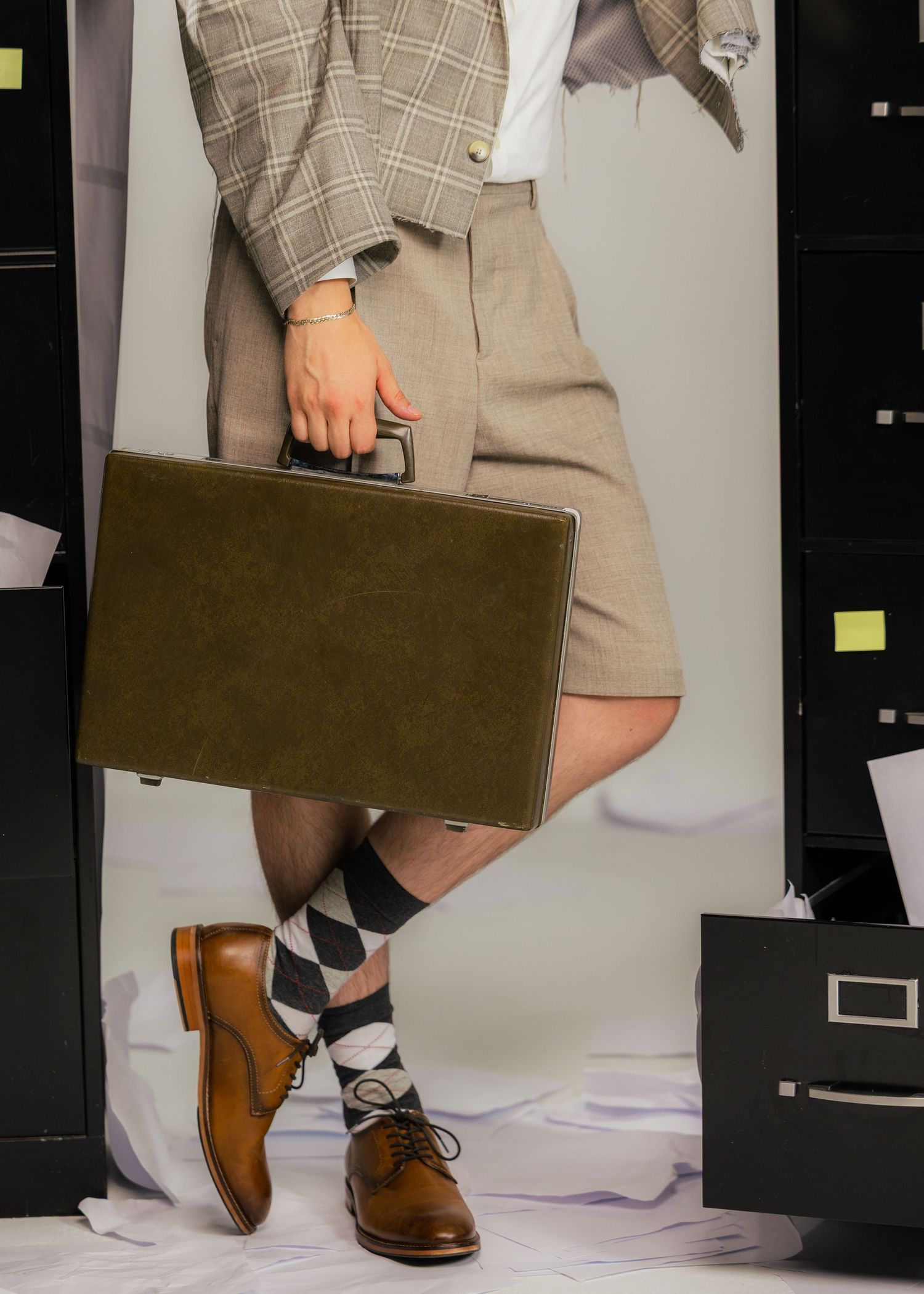 Close-up of brown leather briefcase and plaid suit details.