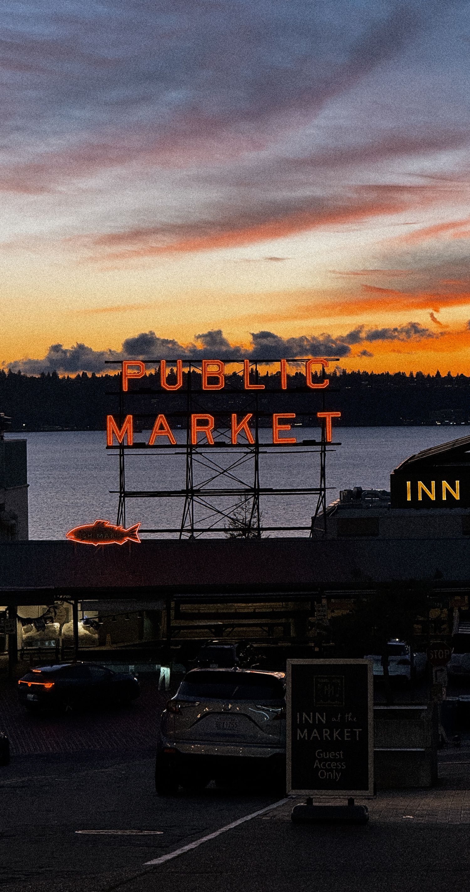 Illuminated Market Inn sign glowing against darkening sunset sky over water.