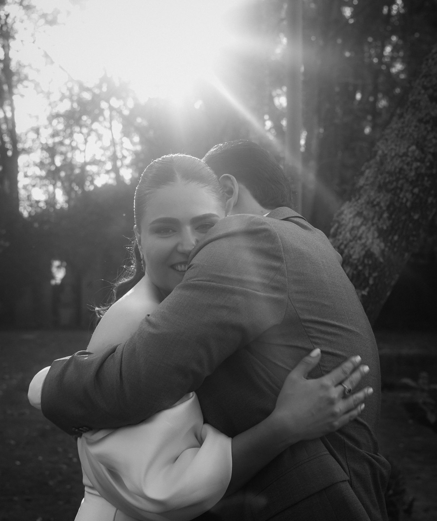 Black and white intimate portrait with sunlight streaming through trees.