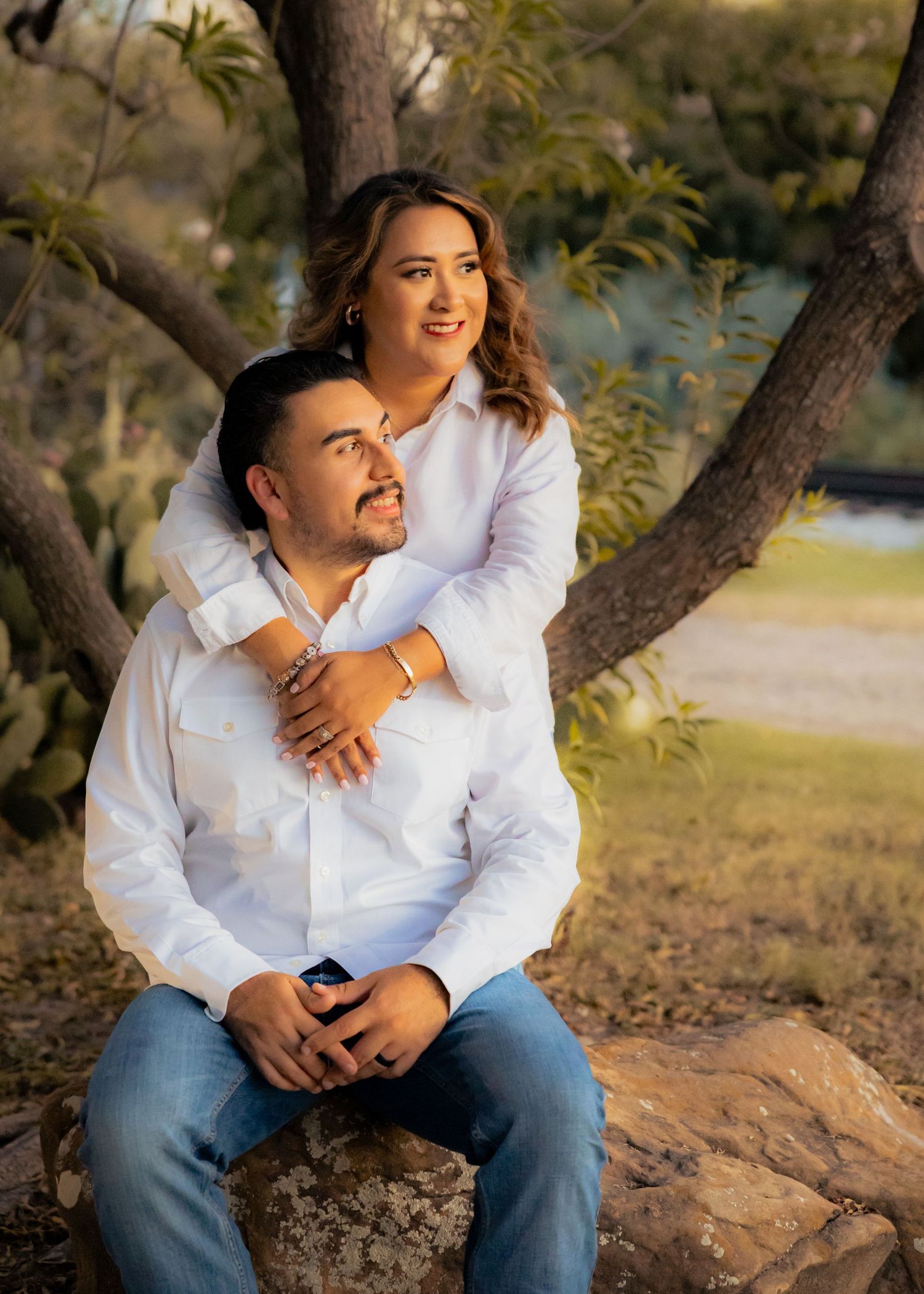 Couple relaxing on rocks by a lake during an outdoor photoshoot.