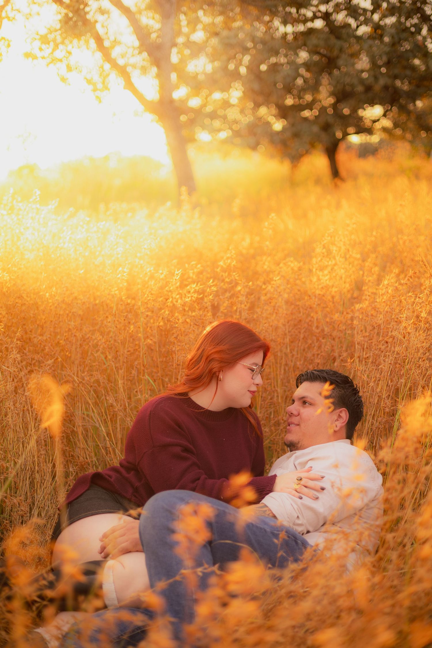 A couple lies together in a golden wheat field at sunset creating a romantic autumn scene.