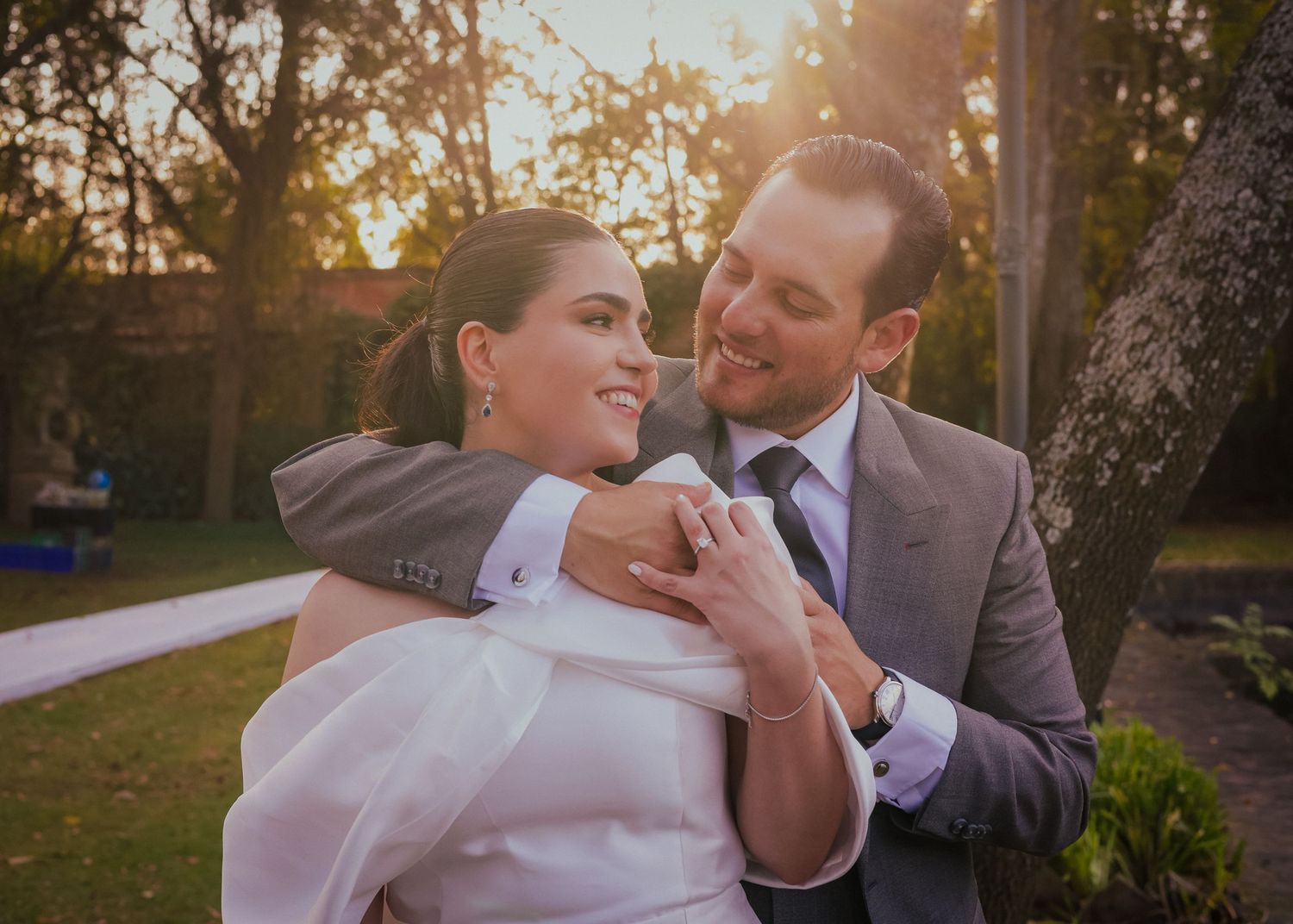 A joyful wedding moment captured during sunset with trees in the background.