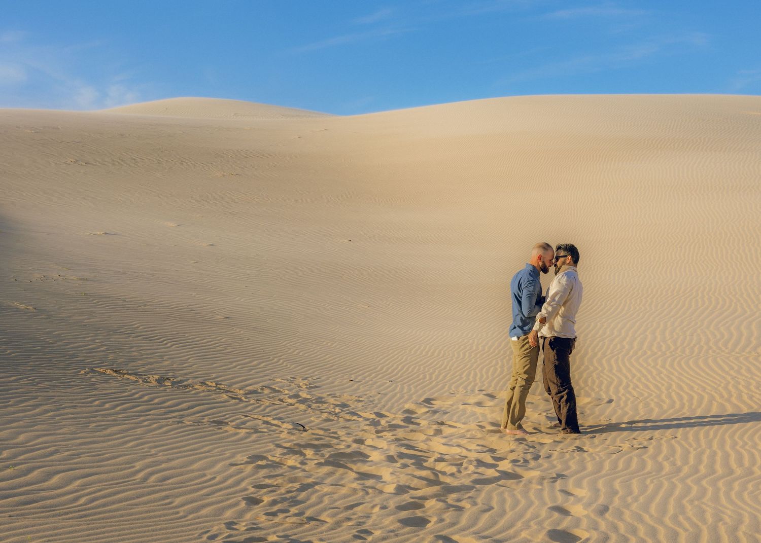 Wide landscape shots of sand dunes with couple in distance.
