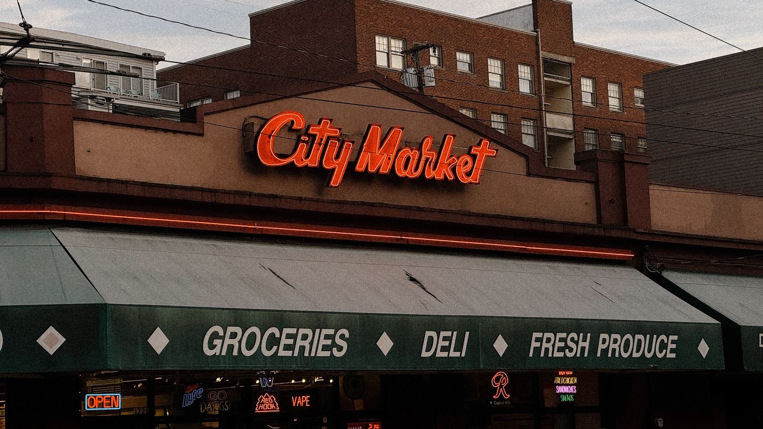 Urban street scene with brick buildings and storefront signs at dusk.