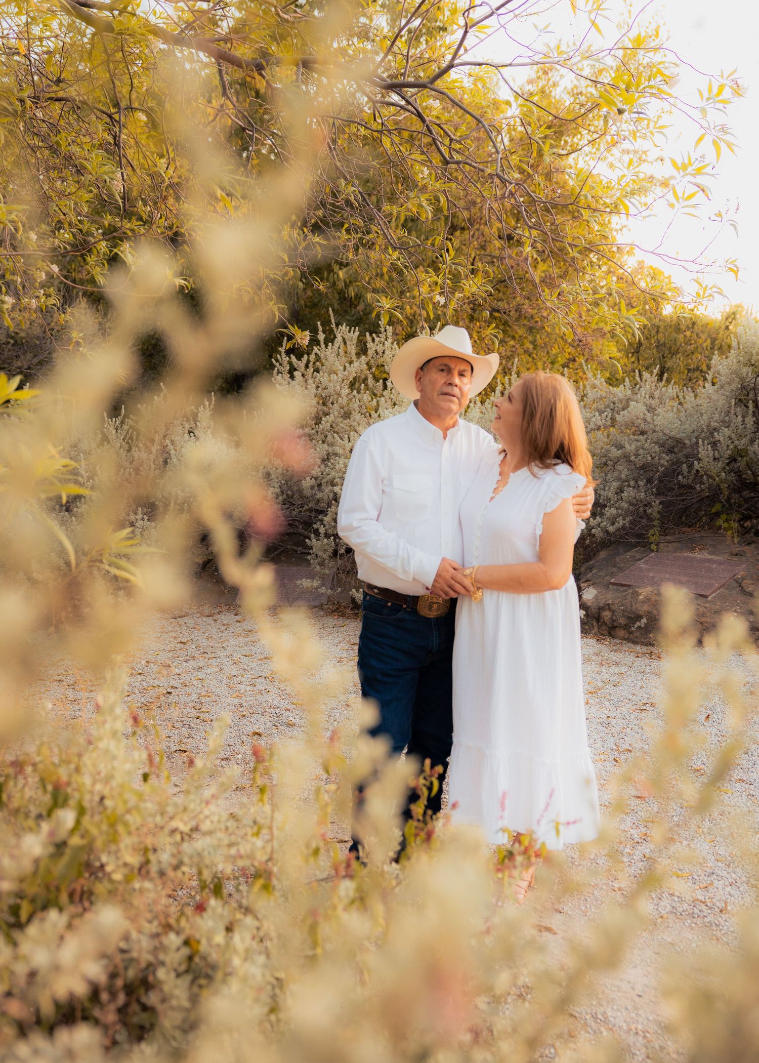 A romantic couple poses among autumn foliage during a golden hour photoshoot.