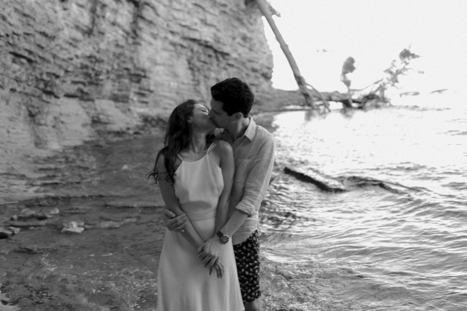 Couple sharing romantic kiss near rocky shoreline with calm water in Cassis, South of France
