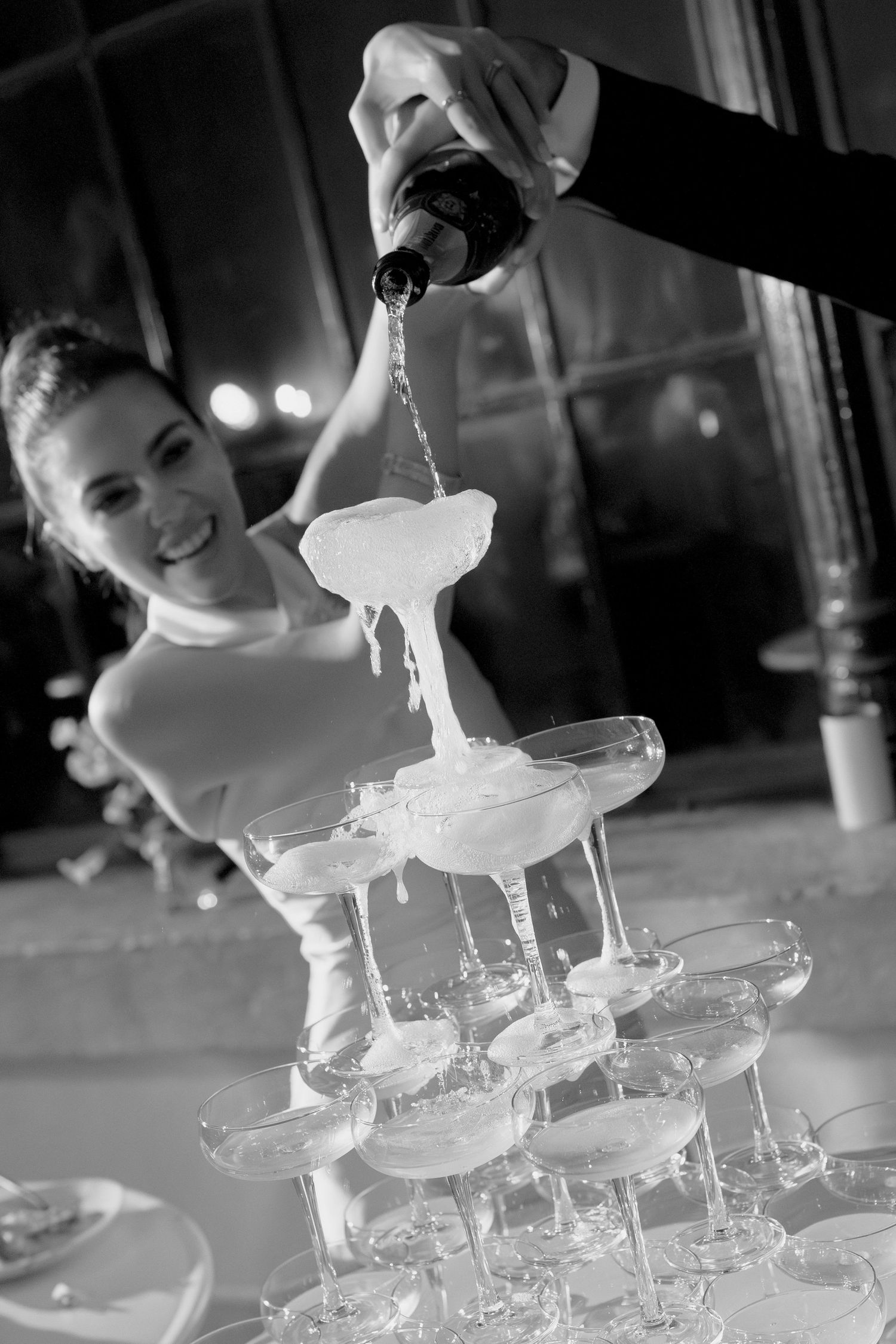 Bride pouring champagne tower during elegant wedding reception