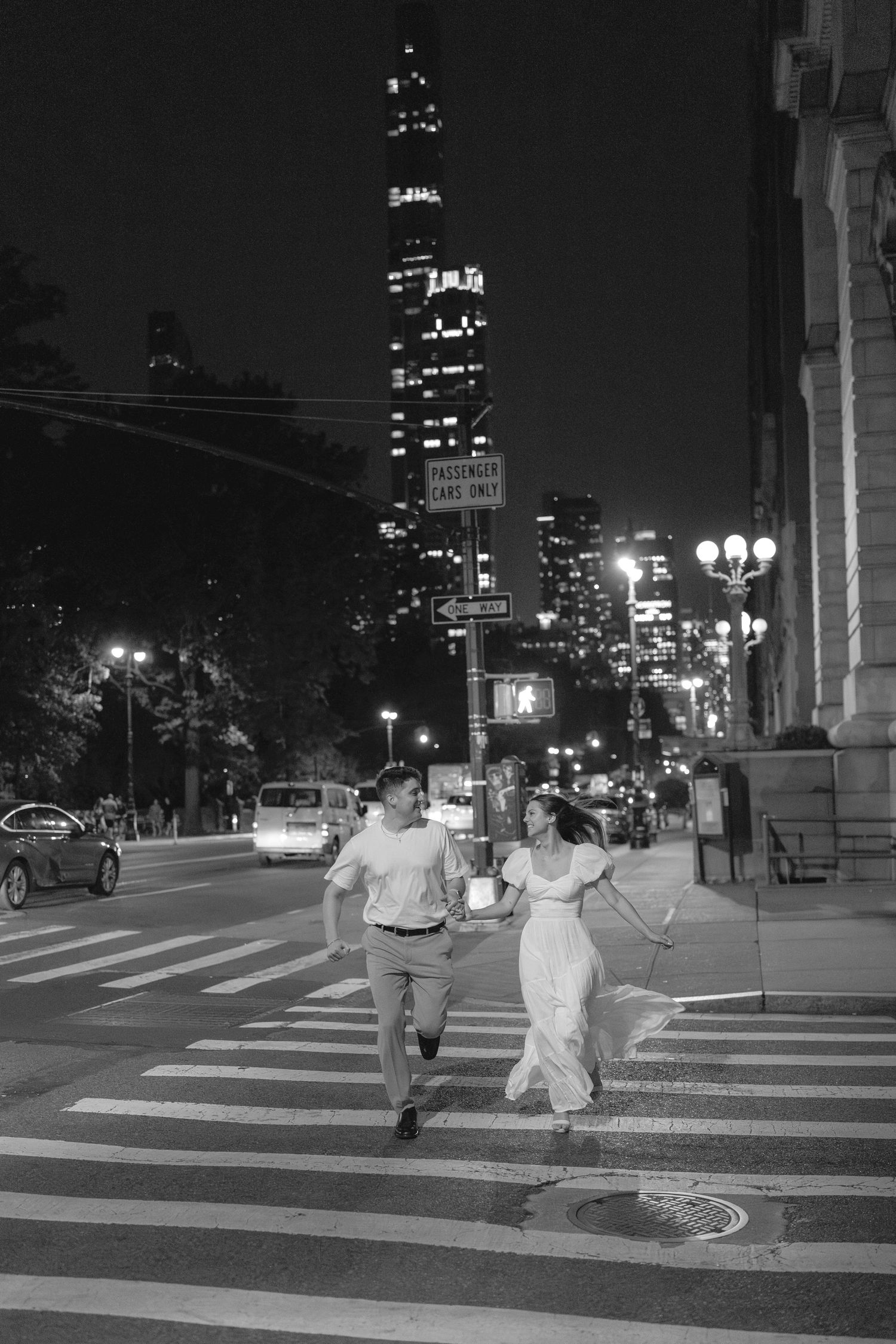 Couple running across city crosswalk at night in New York City