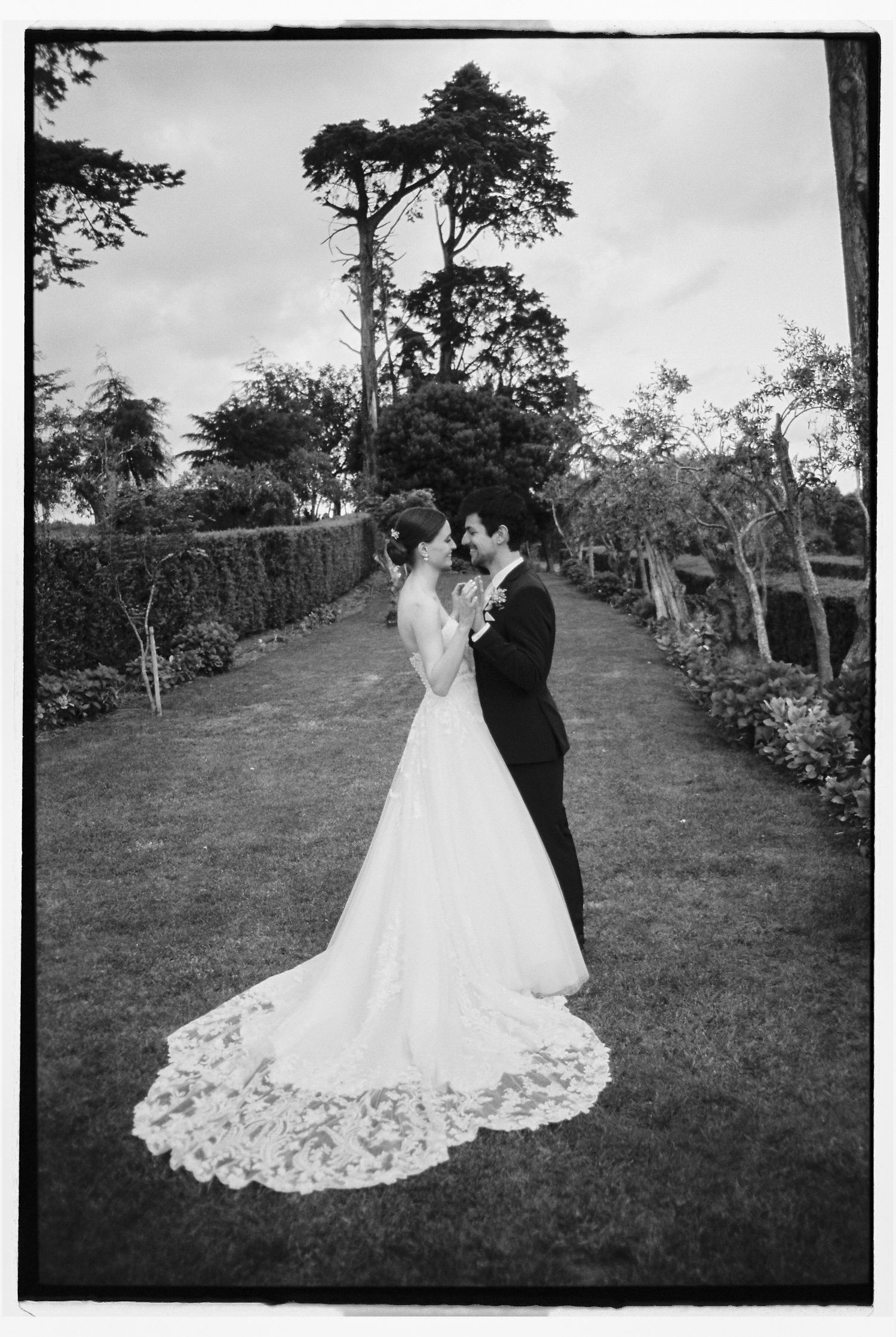 Bride and groom sharing romantic moment on garden pathway during wedding in Portugal countryside