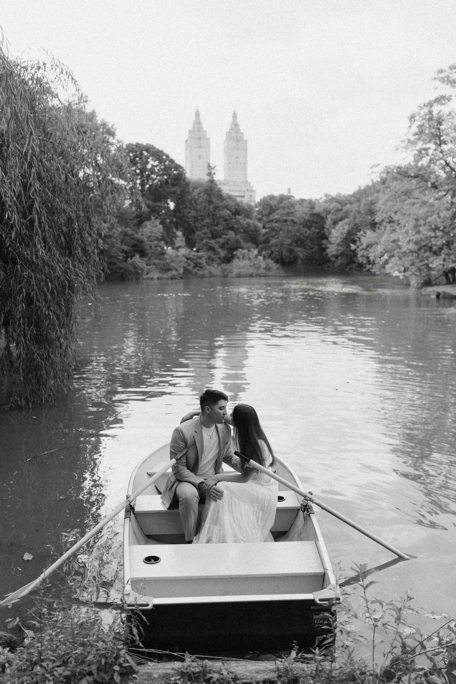 Couple rowing boat on lake in Central Park with New York City skyline in background