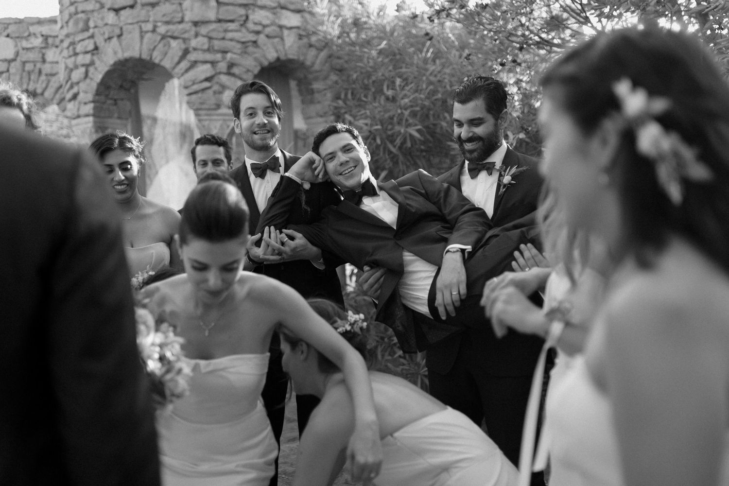 Candid black and white photo of wedding party laughing and celebrating outdoors in Cassis, France