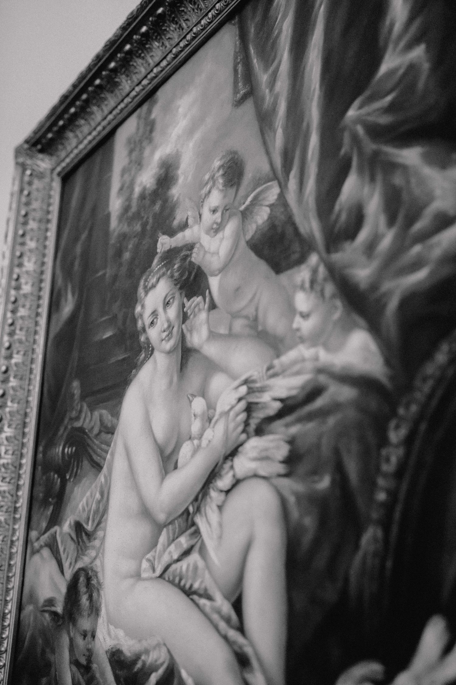 Black and white photo of classical oil painting depicting reclining woman with cherubs