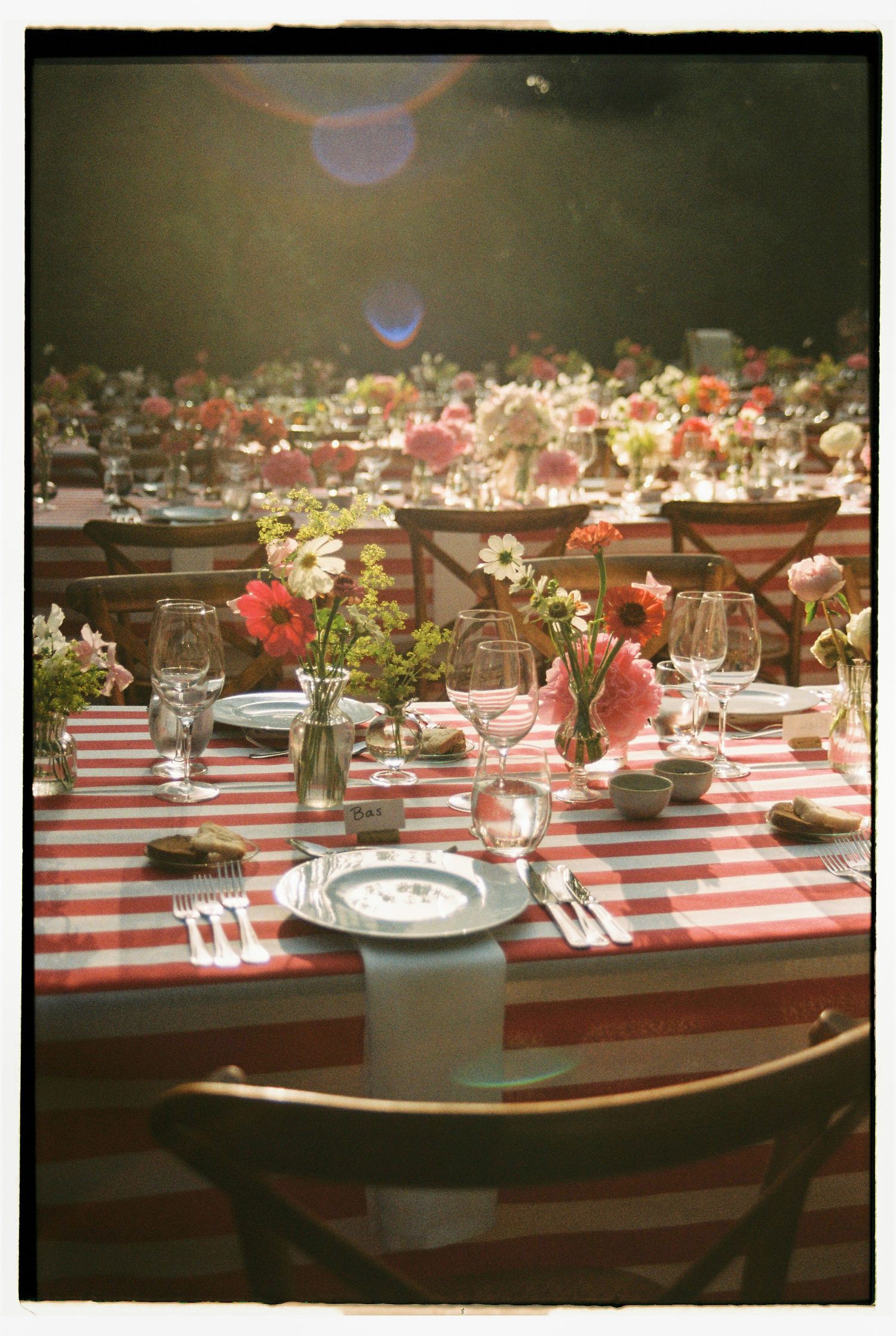 Wedding reception tables with red gingham tablecloths and pink floral centerpieces
