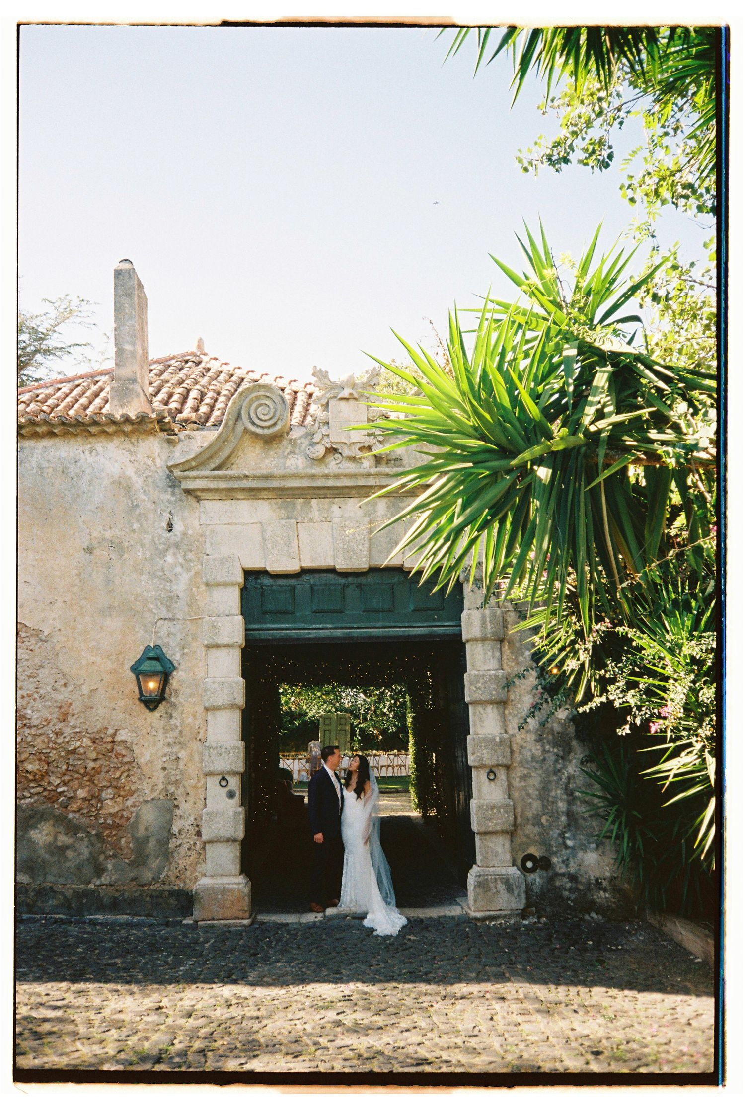 Bride and groom sharing intimate moment under ornate stone archway at historic wedding venue in Lisbon, Portugal