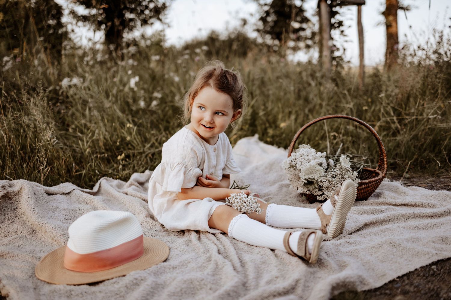 Mädchen auf Picknickdecke mit Hut
